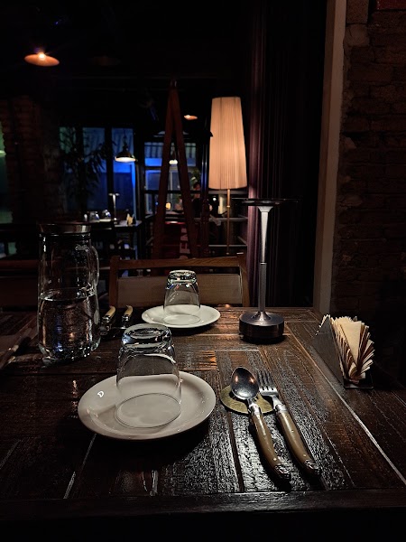 Rustic wooden table set for dinner with inverted glassware and warm accent lighting