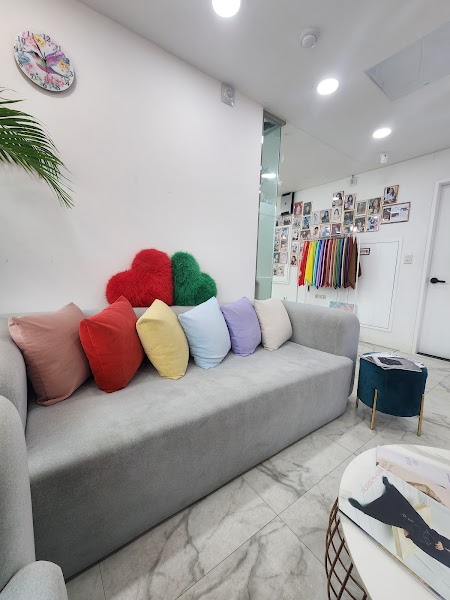 Studio waiting lounge area with sofa, colorful seasonal cushions, and fabric sample racks