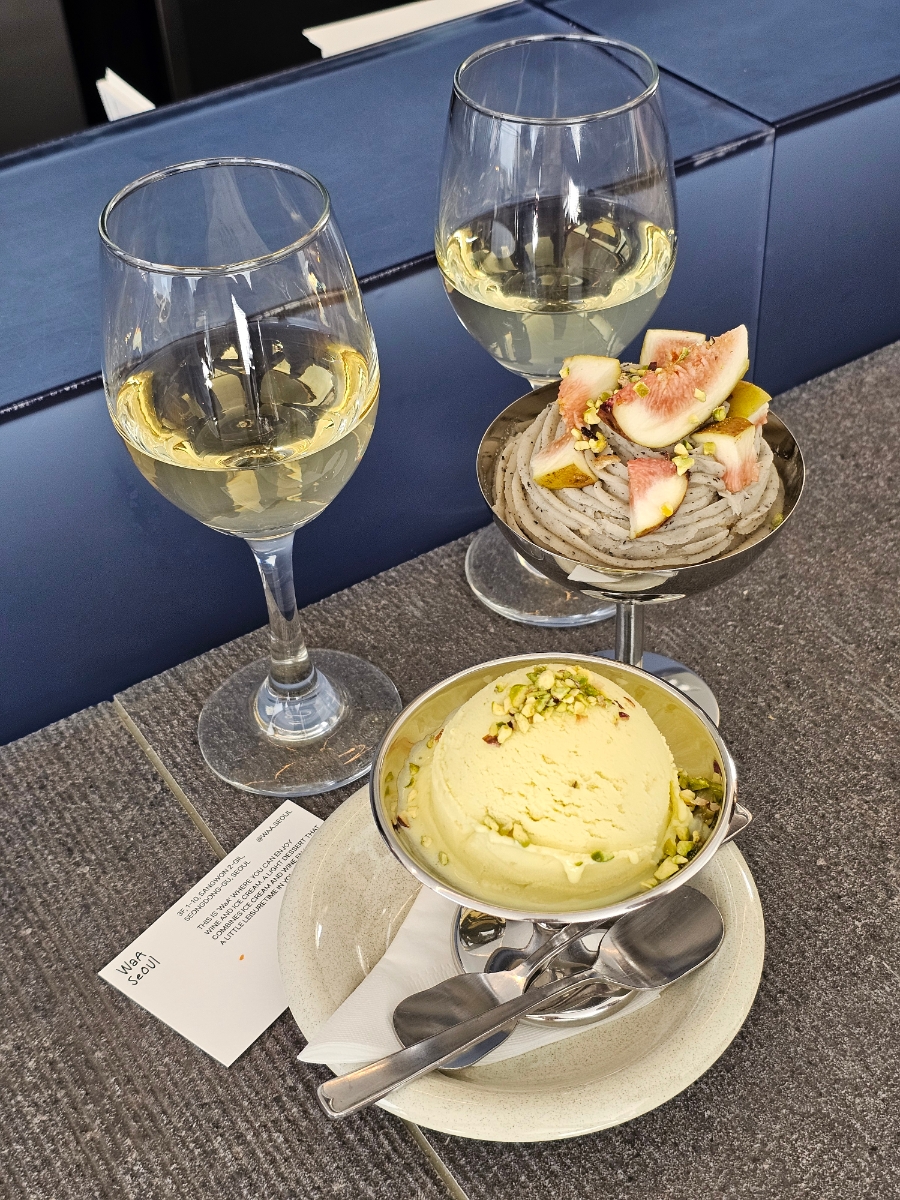 Two glasses of white wine with fig mont blanc and pistachio ice cream served on textured table at Waa Seoul