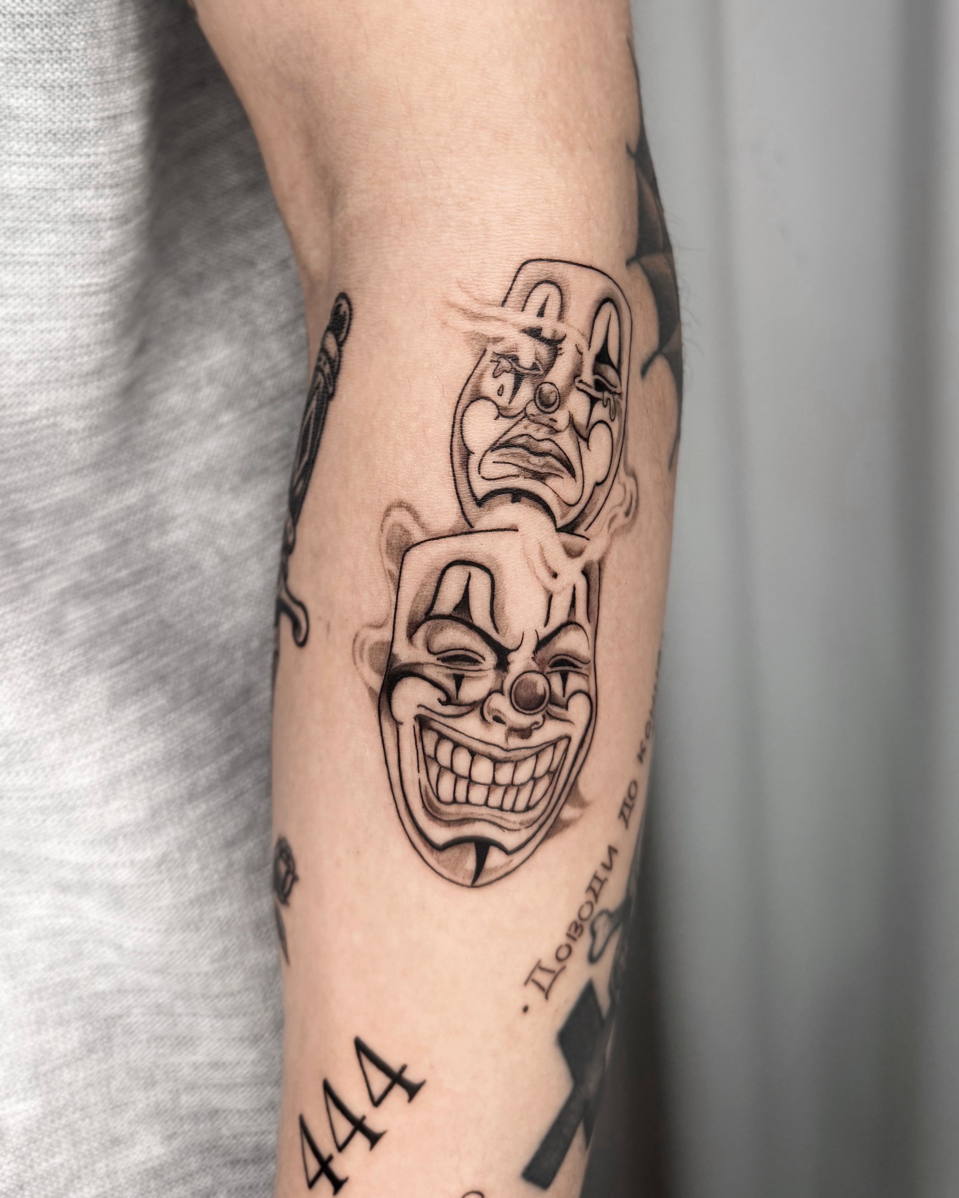 Black and grey theatrical clown masks tattoo on arm