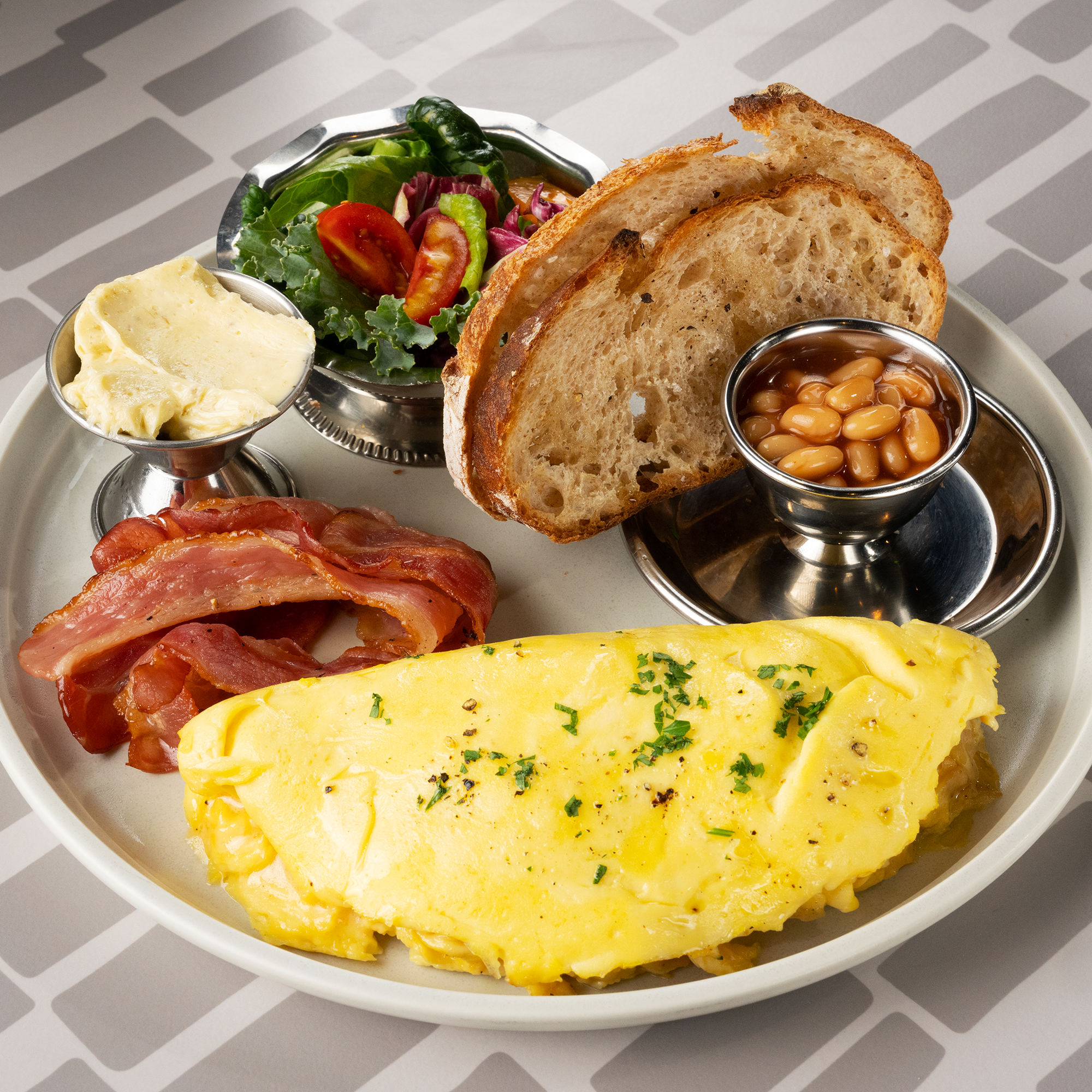 Brunch plate with folded herb omelet, toasted rustic bread, side salad, and fresh beans