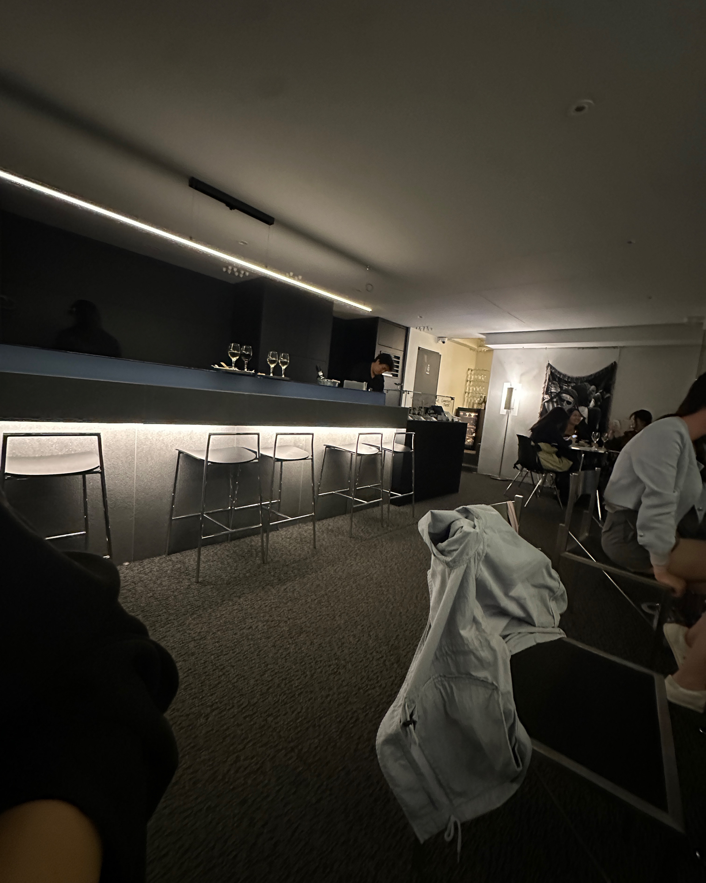 Moody modern wine bar interior with sleek counter, bar stools, and warm under-counter lighting