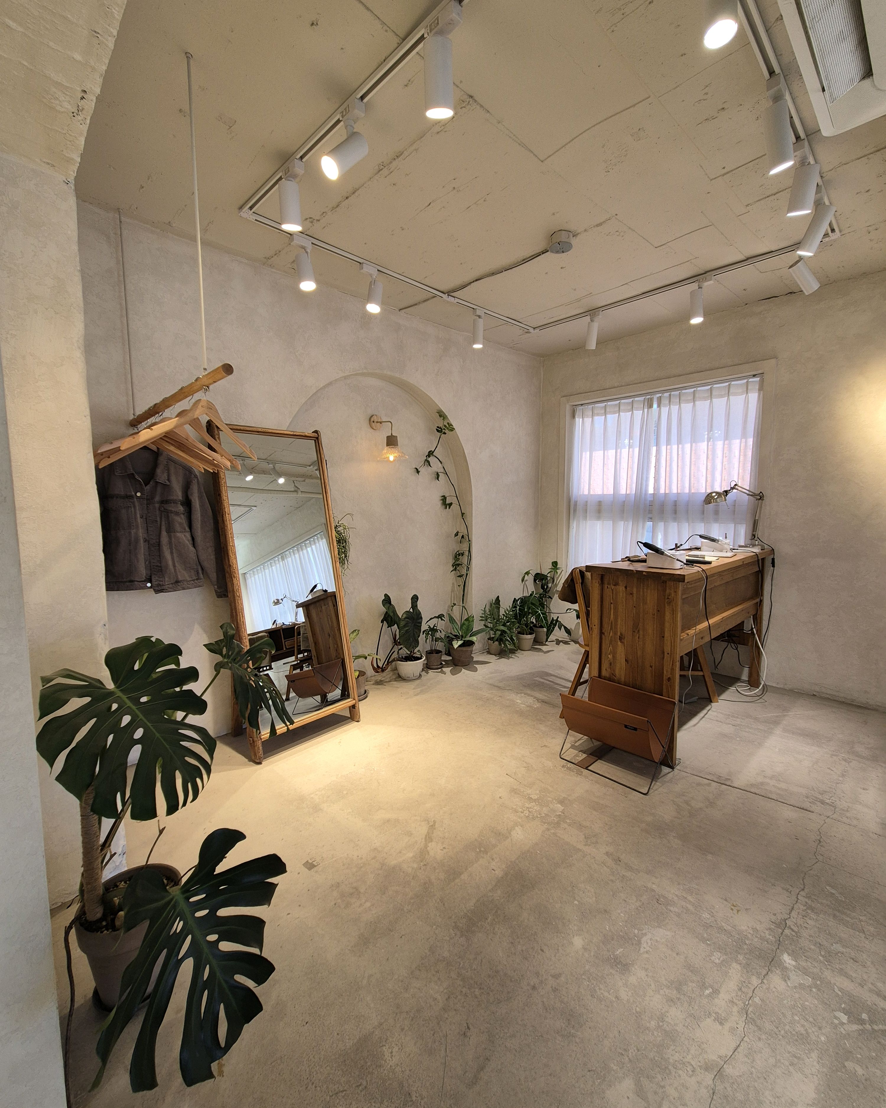 Clean studio interior featuring full-length floor mirror, birch crafting benches, and potted plants