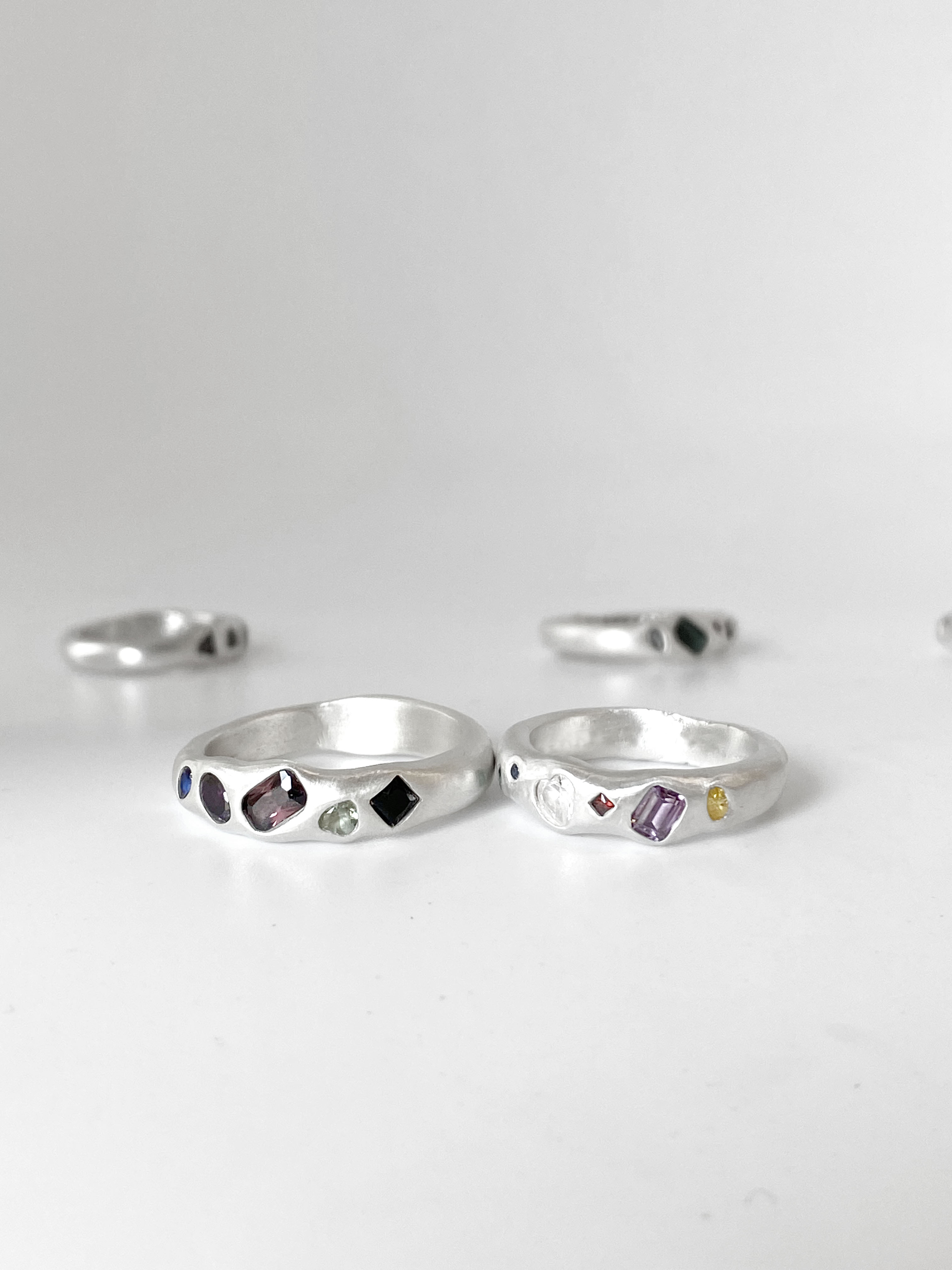 Two organic silver rings with multicolored faceted gemstones placed side by side