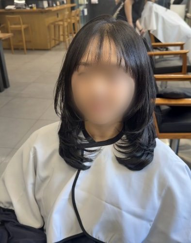 Client with layered black hair sitting in styling chair