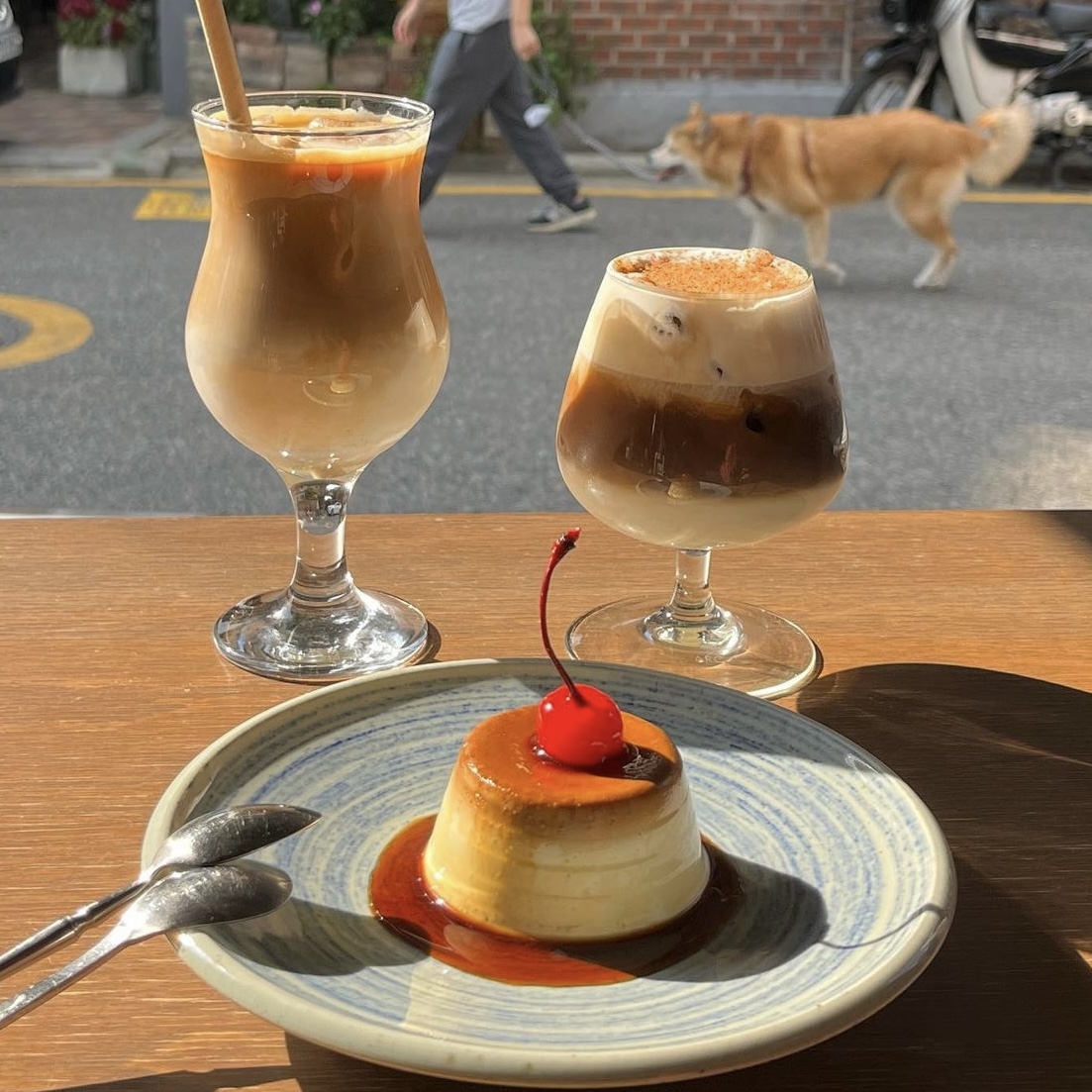 Pudding and iced coffees on a wooden terrace table overlooking the street