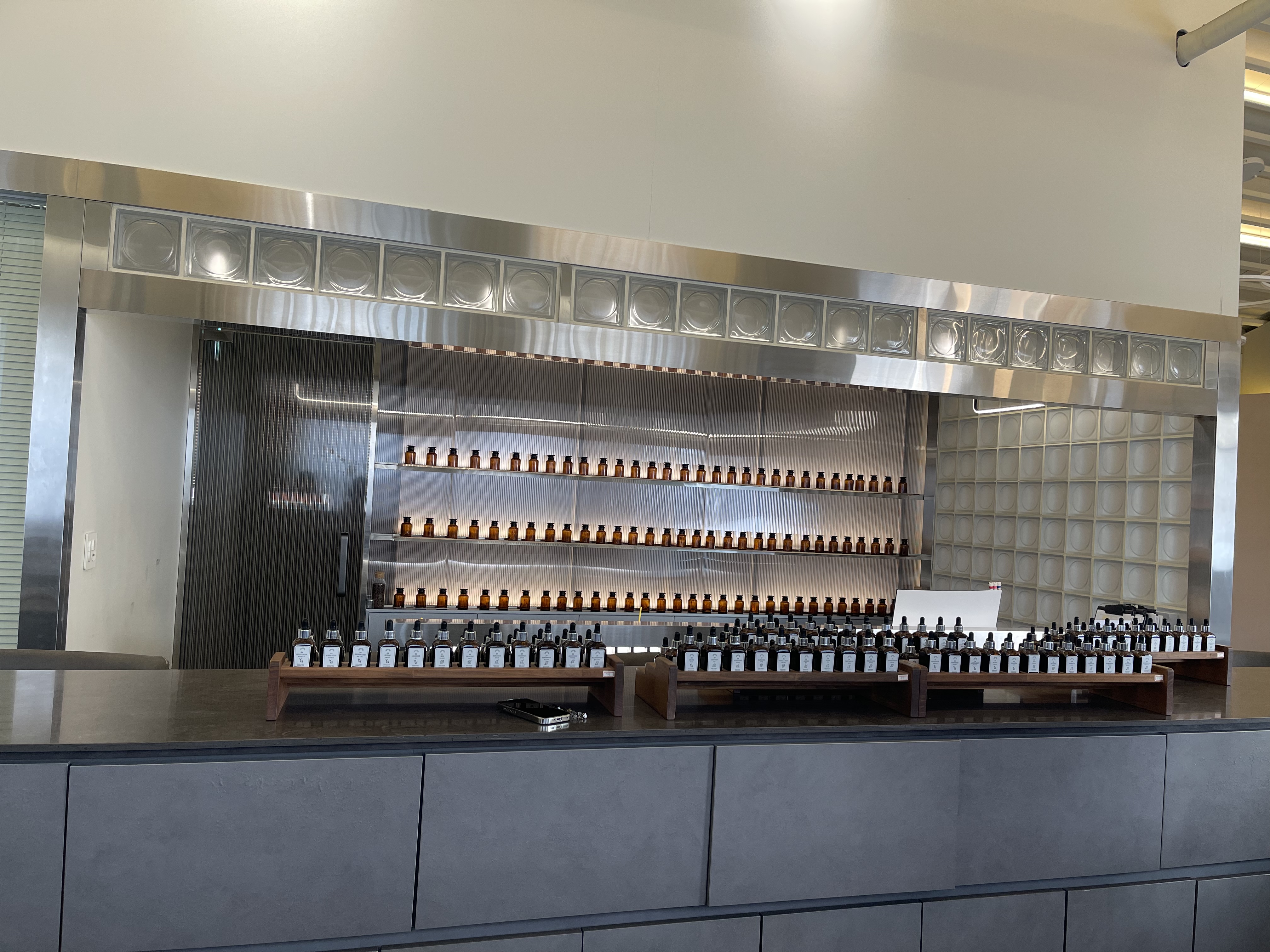 Modern minimalist studio interior with organized rows of perfume vials on stainless shelves