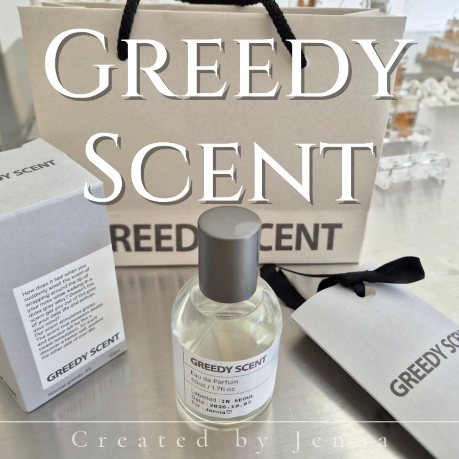 A perfume bottle, box, and shopping bag from Greedy Scent on a metallic table