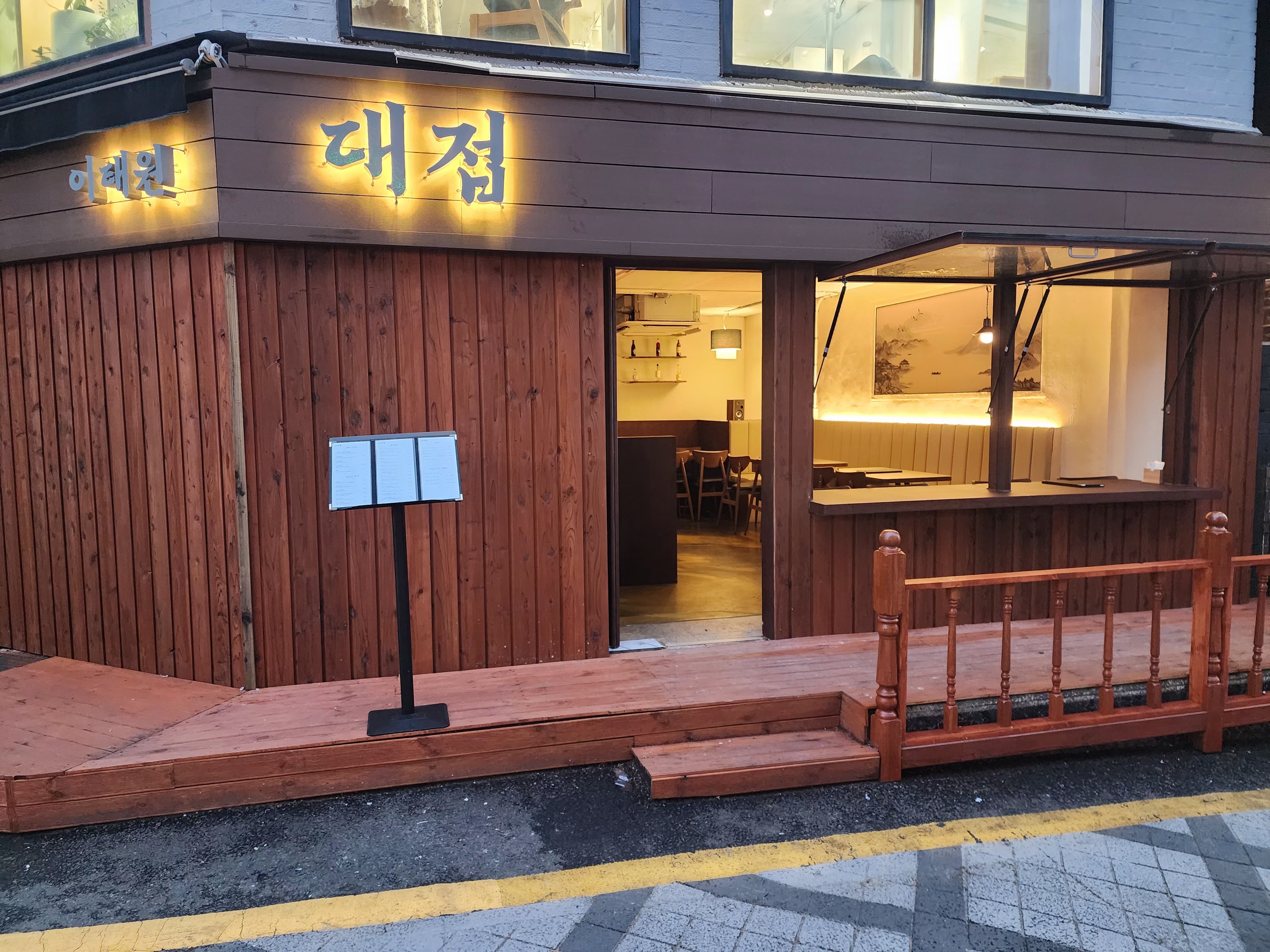 Exterior storefront of Daejeop with vertical wood paneling and warm illuminated signage