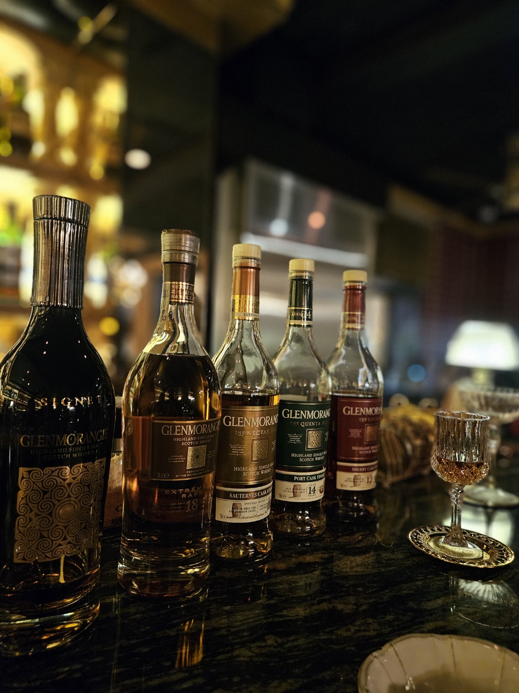 Curated bottles of single malt whisky on a dark marble counter