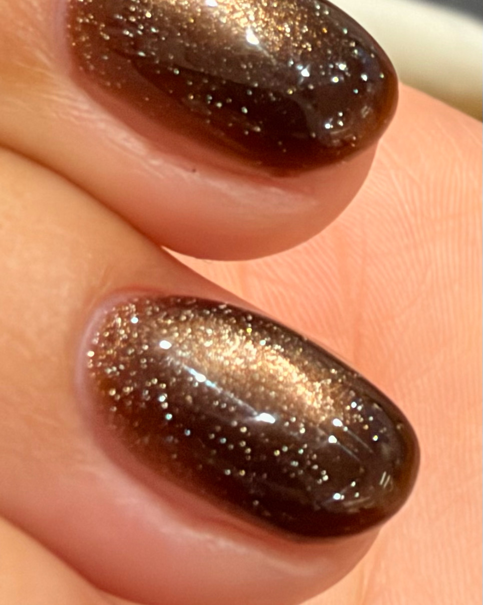 Macro detail of glossy brown glitter cat-eye nail art