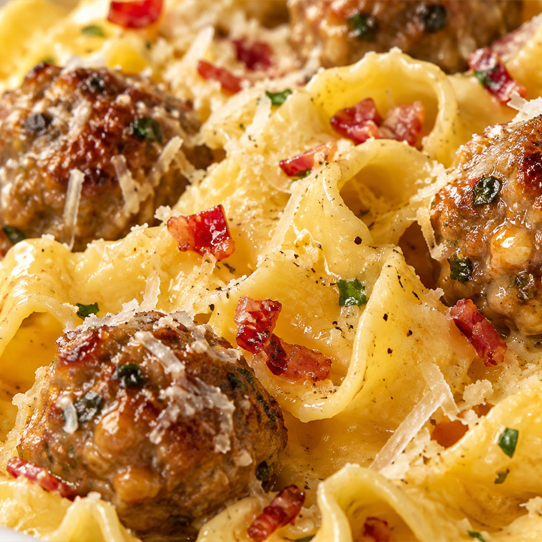 Creamy pasta tossed with meatballs, bacon bits, and grated cheese