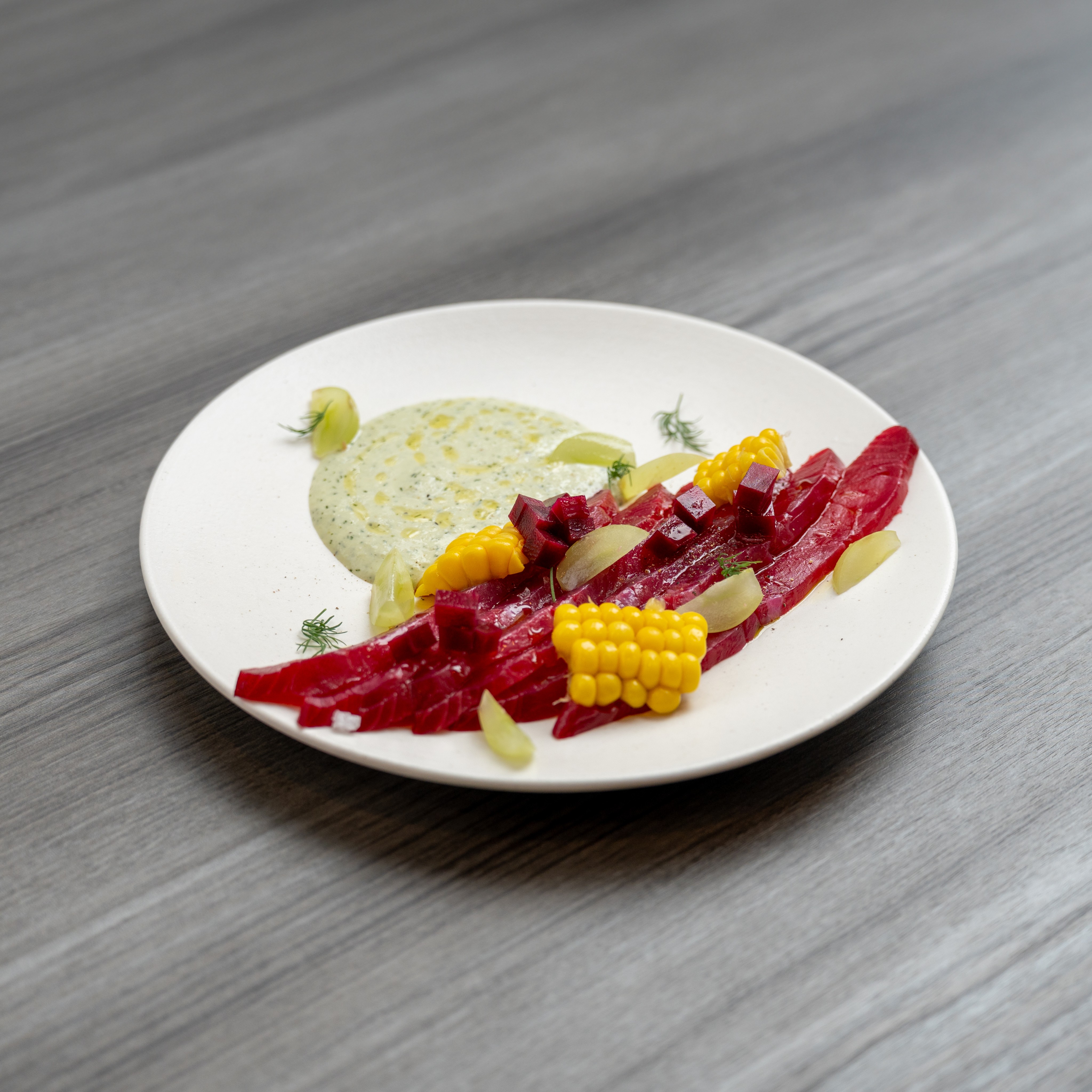 Artisanal beet and corn appetizer with herbal cream sauce