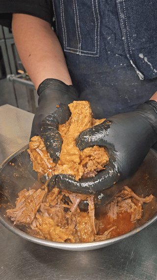 Hand-pulling and mixing seasoned slow-cooked meat in the XOLO kitchen