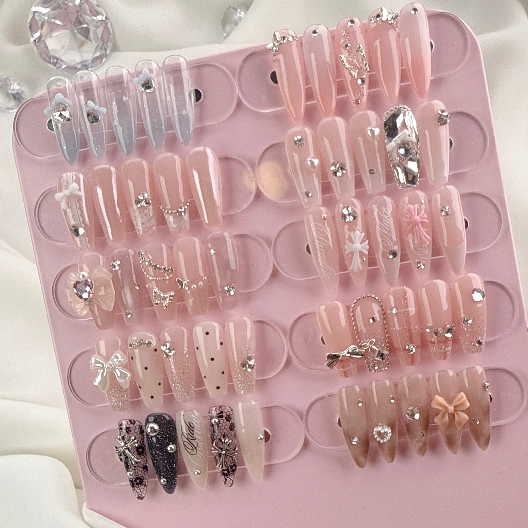 Curated press-on nail art designs with charms and rhinestones on display board
