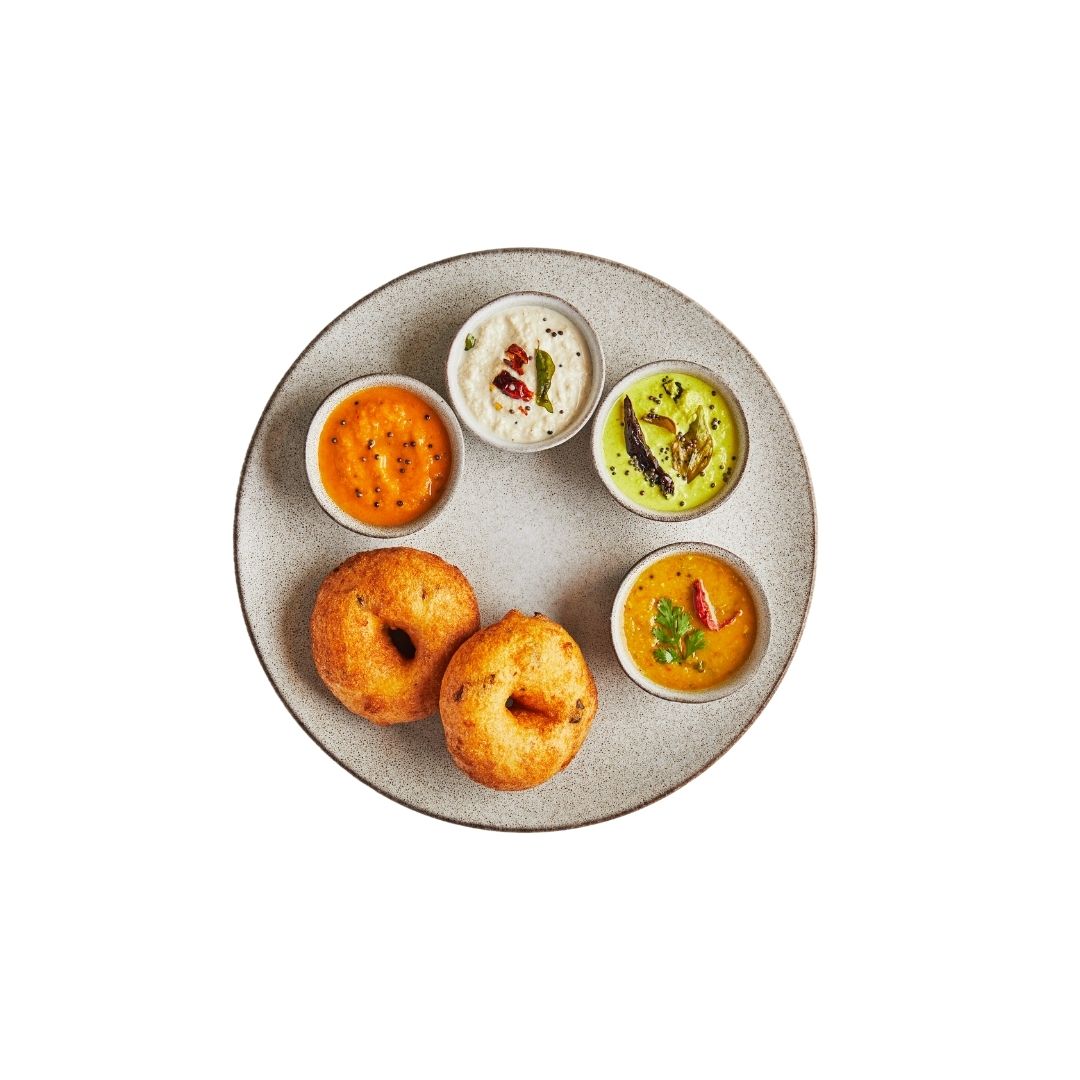 Crisp medu vada lentil fritters served with four colorful dipping chutneys