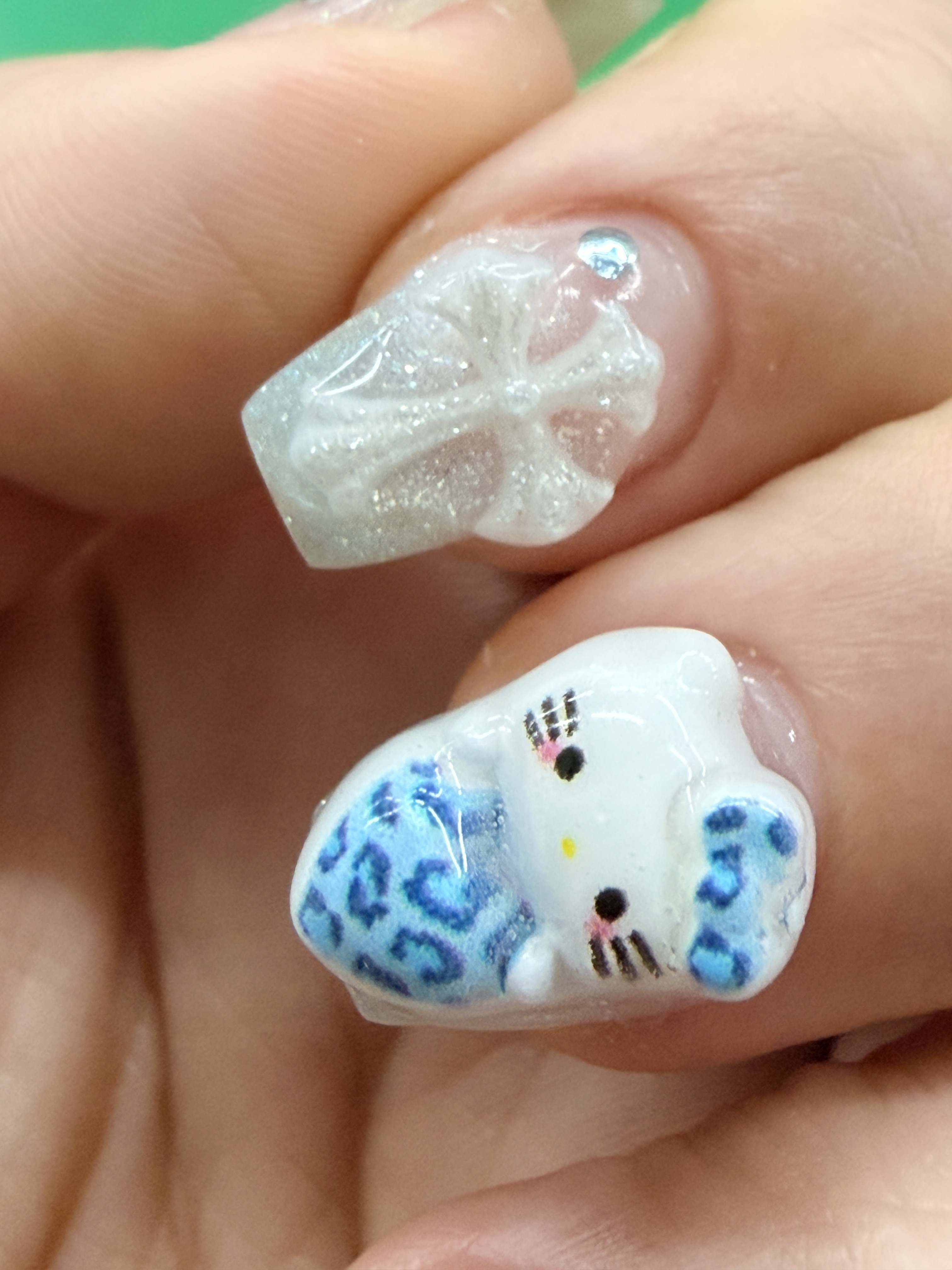 Detailed 3D nail art featuring custom relief cross emblem and crystal accents
