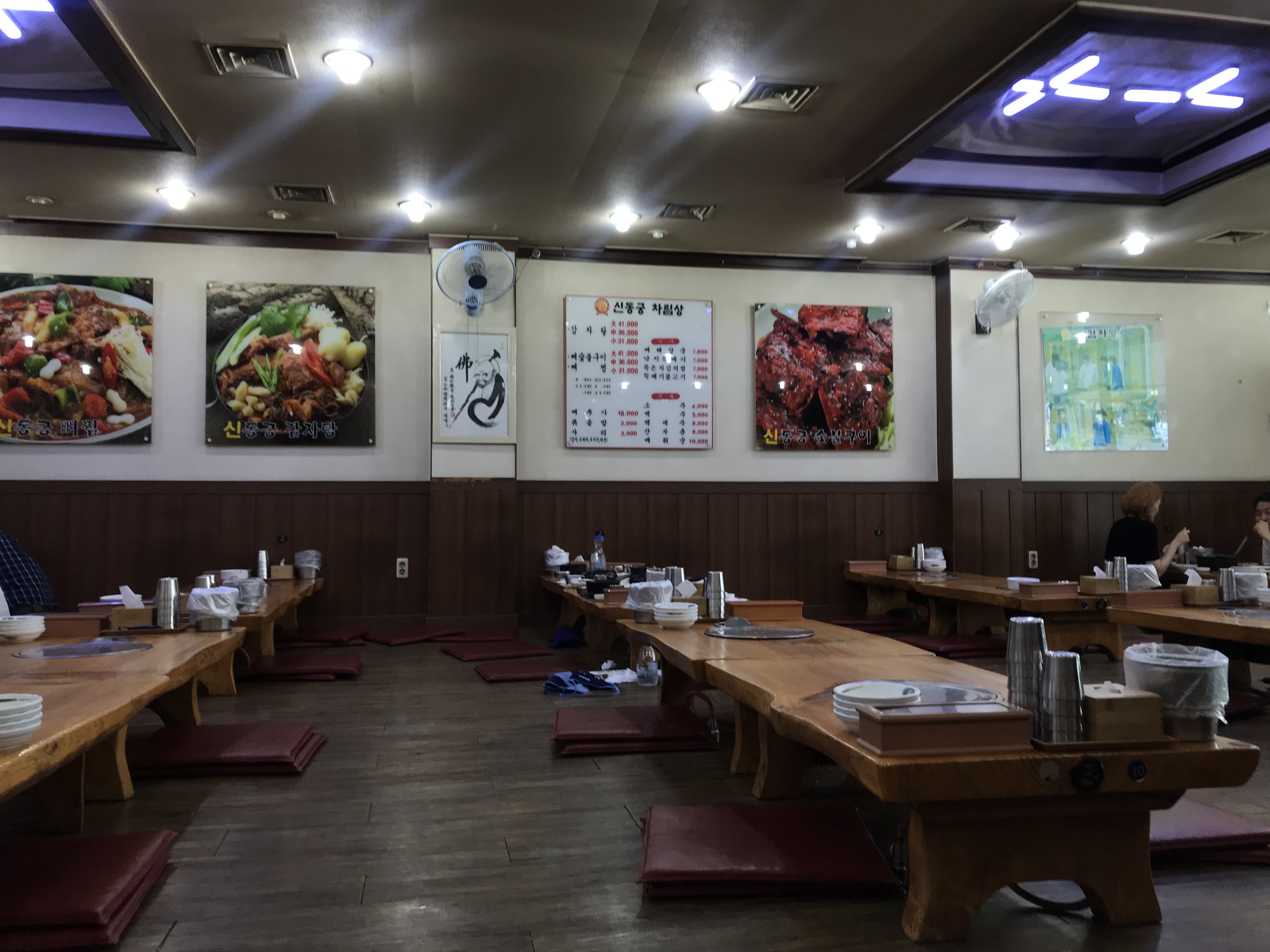 Interior of Shindonggung Gamjatang restaurant in Yeoksam with low wooden tables and floor cushions.