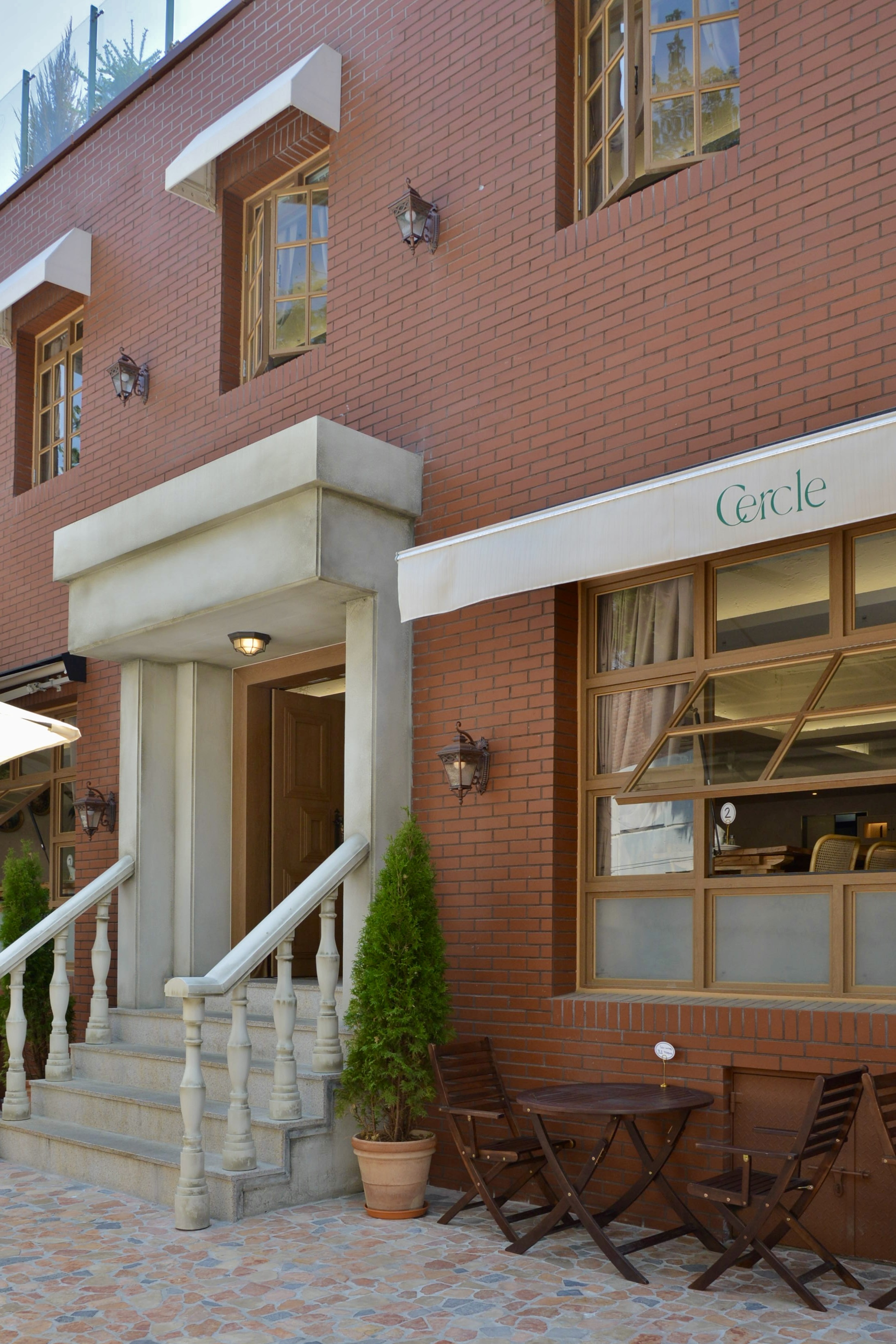 Entrance of Cercle Hannam with brick exterior, classic stone staircase, and outdoor seating.