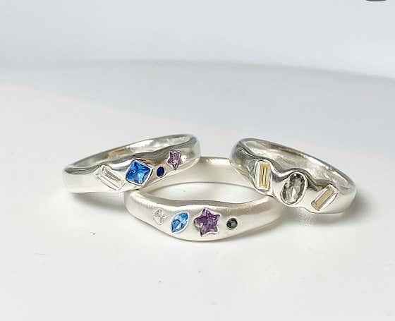 Three handmade silver rings with embedded colorful gemstones and star-shaped accents