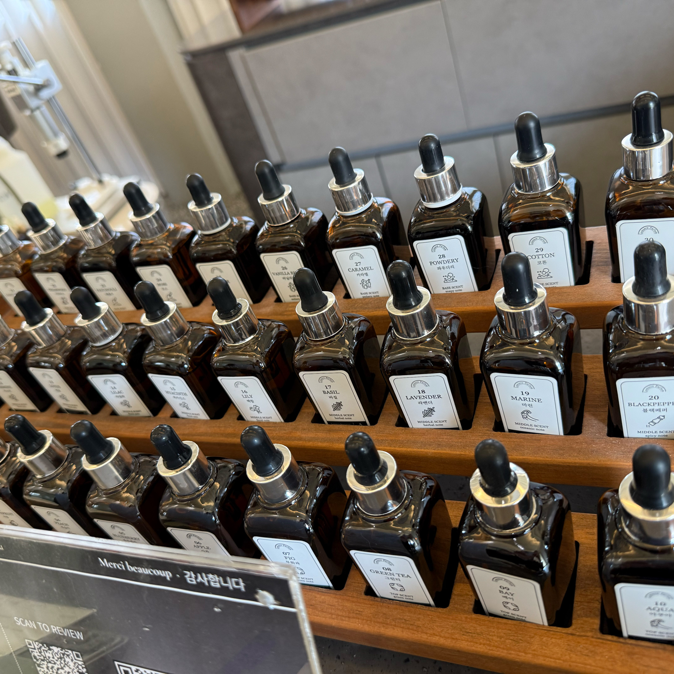 Rows of amber glass perfume bottles with dropper caps arranged in a tiered wooden display rack