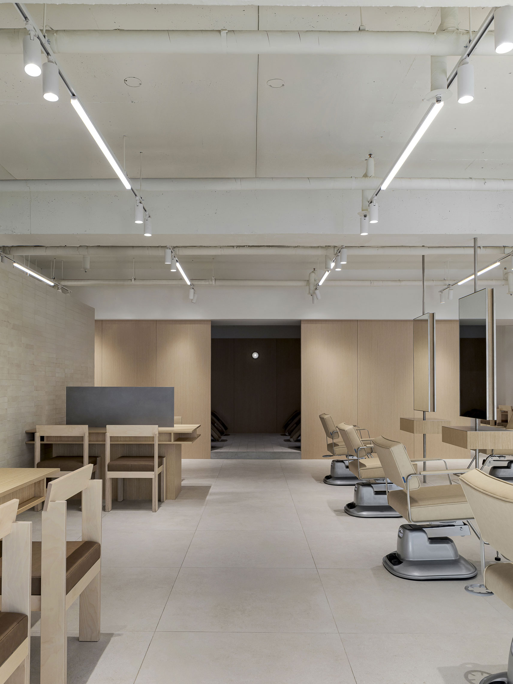 Modern interior of More On Hair salon with light wood accents and styling chairs.