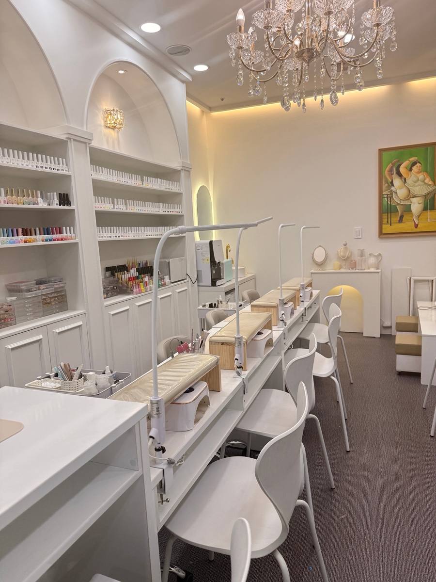 Interior of modern nail salon with white workstations and organized lacquer shelves