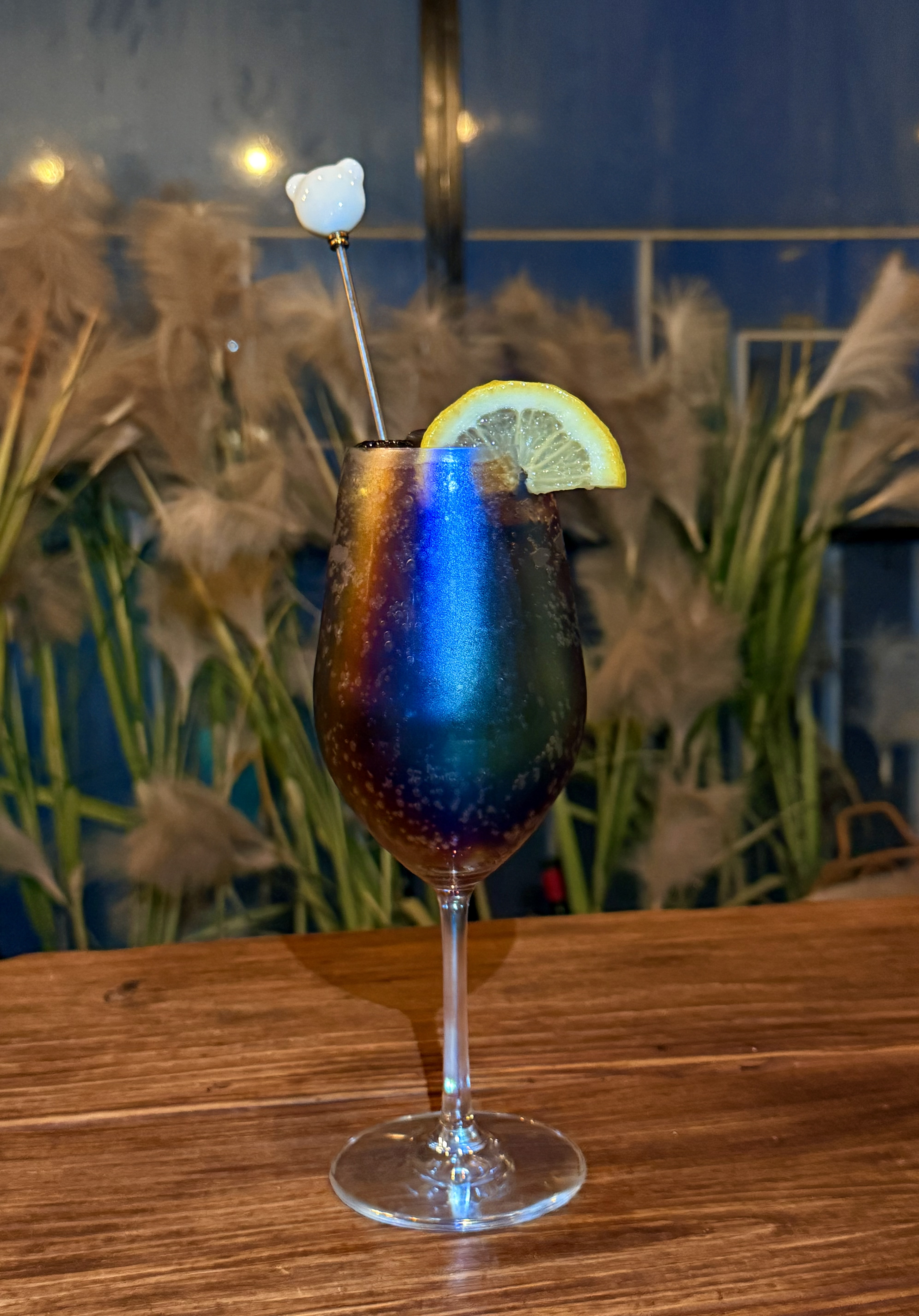 Stemmed cocktail glass with iridescent sheen and lemon wedge