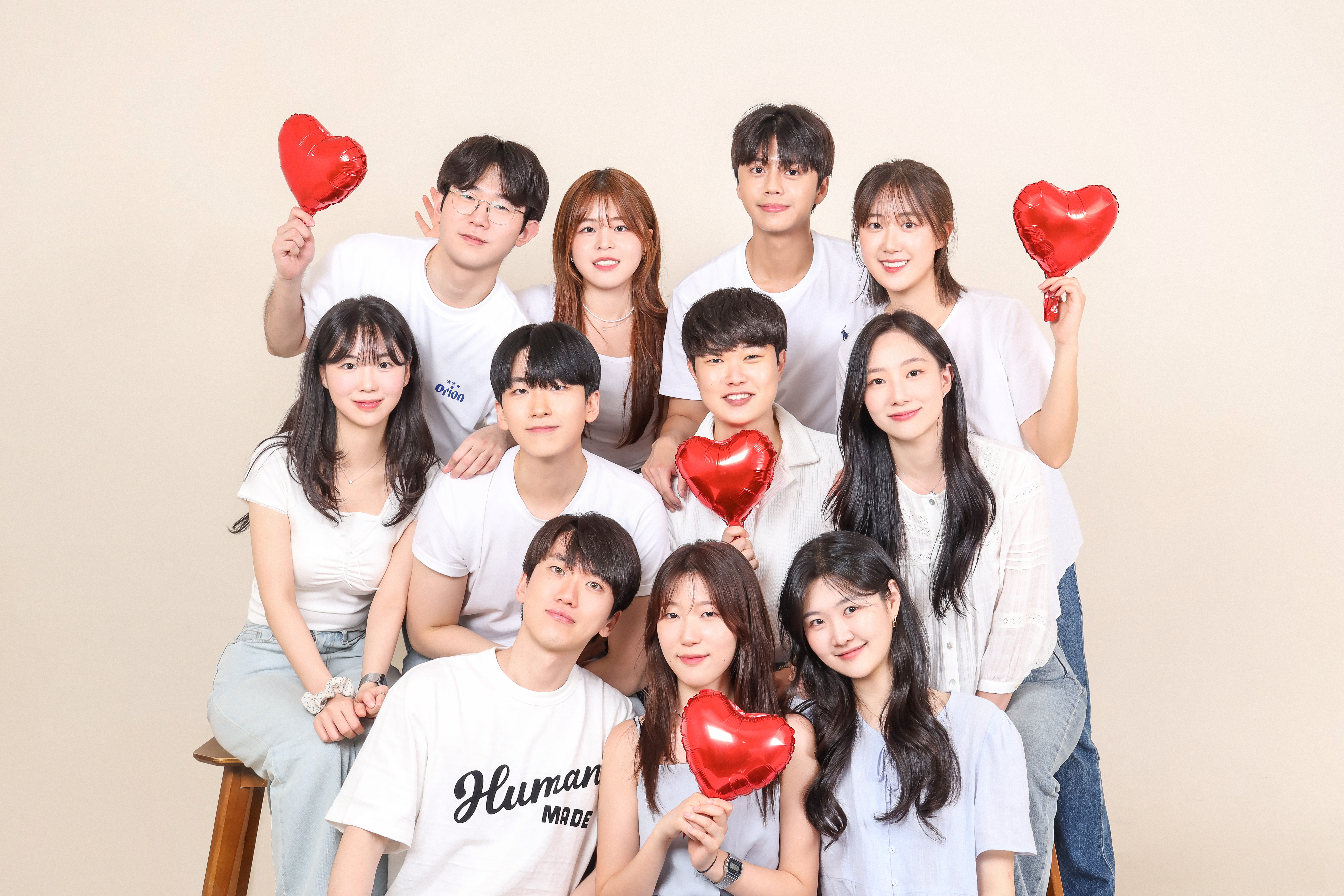Group of friends in white shirts holding red heart balloons