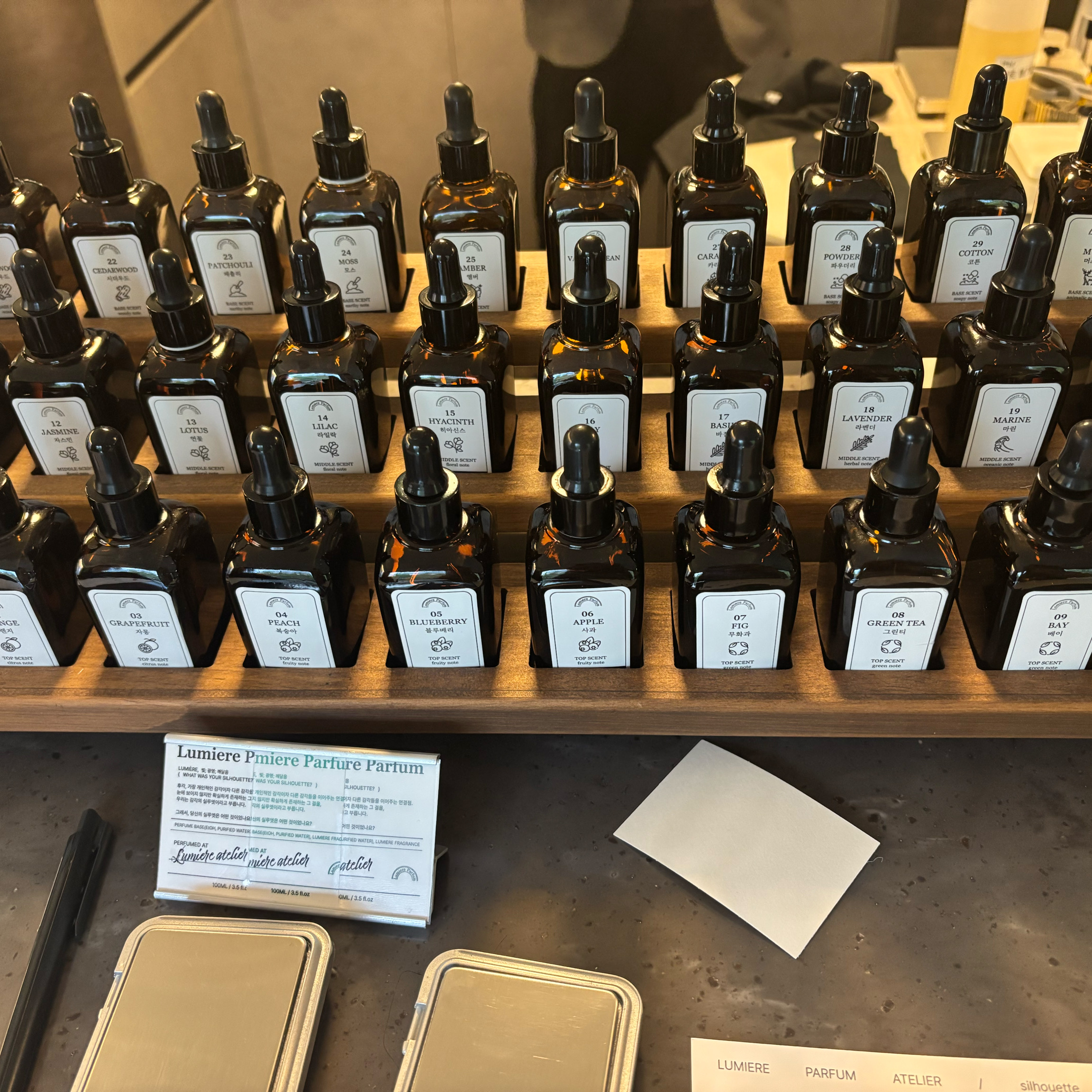 Rows of amber glass dropper bottles on a stepped wooden display rack in the Hongdae workshop