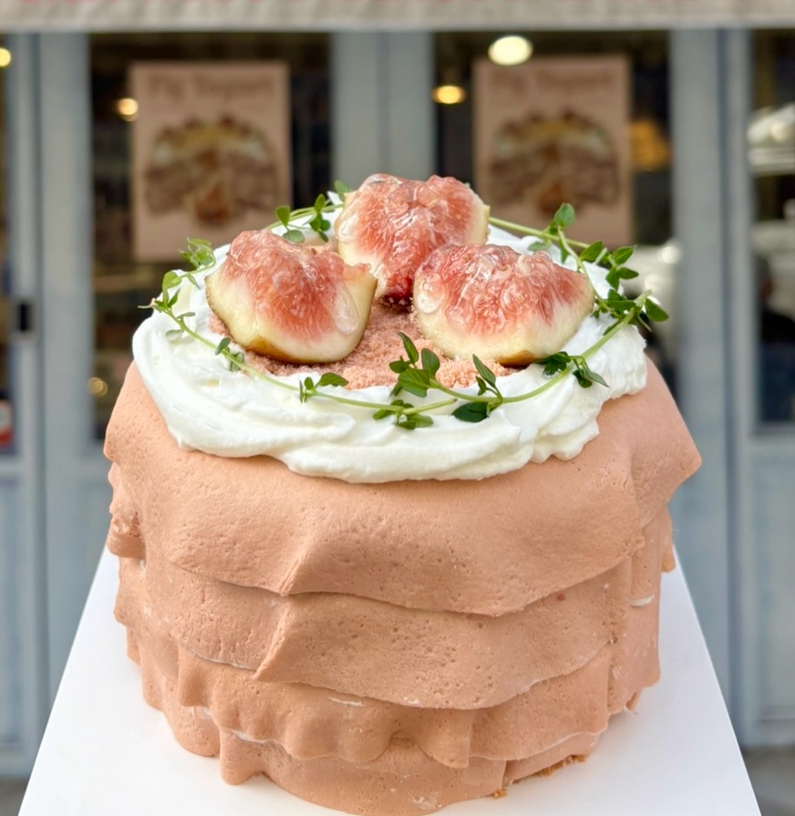 Decorated fig layer cake on white pedestal