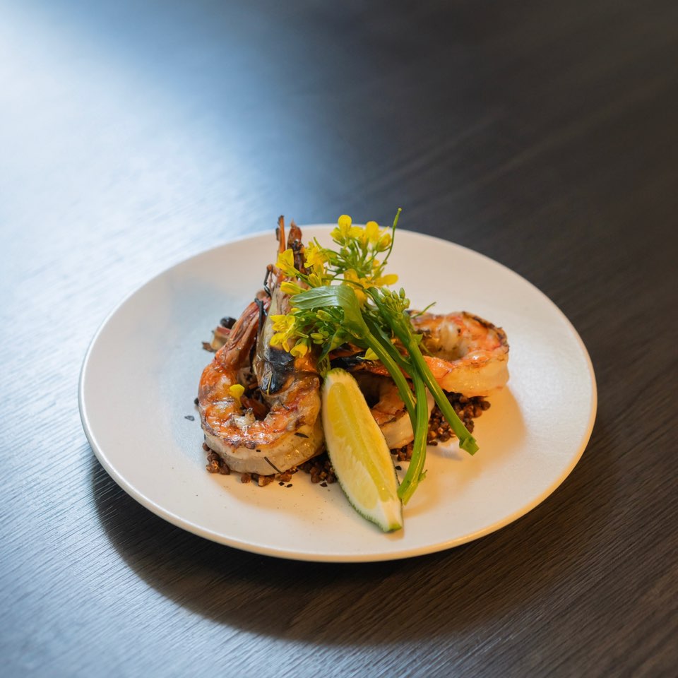 Grilled prawns plated with lime and floral herbs