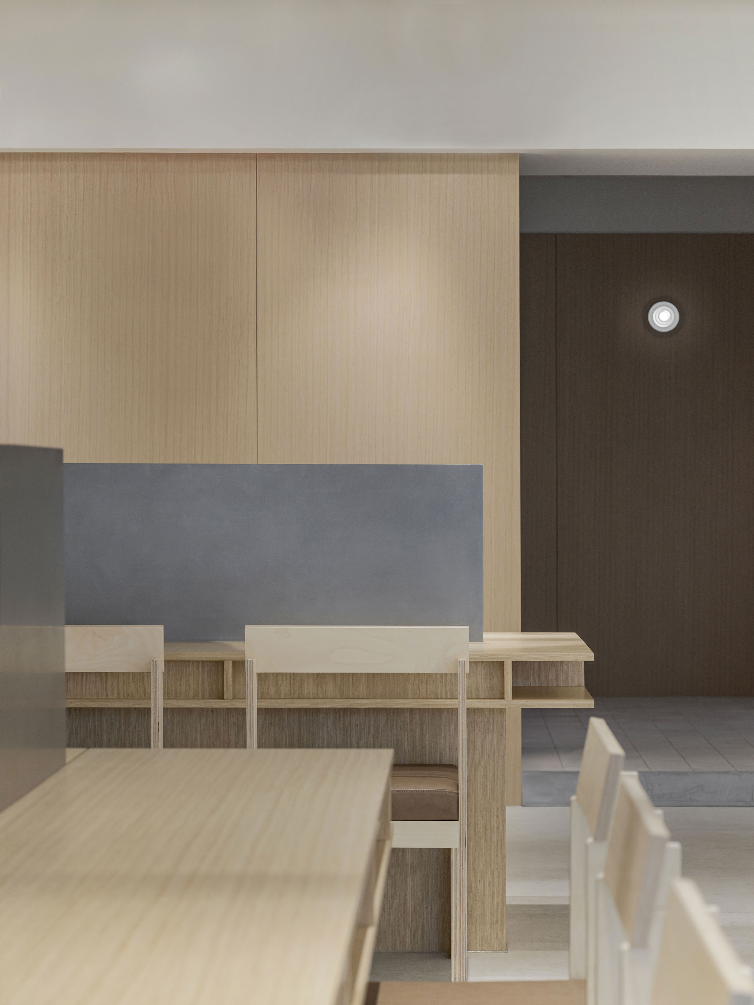 Minimalist interior with light wood panels and solid matte grey partitions at MORE ON HAIR.