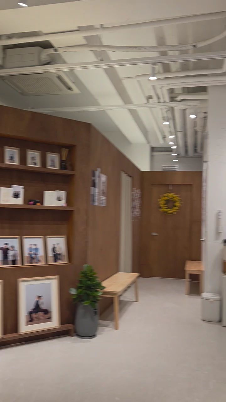 Interior of a photo studio featuring wood-paneled walls, framed photos on shelves, and minimalist furniture