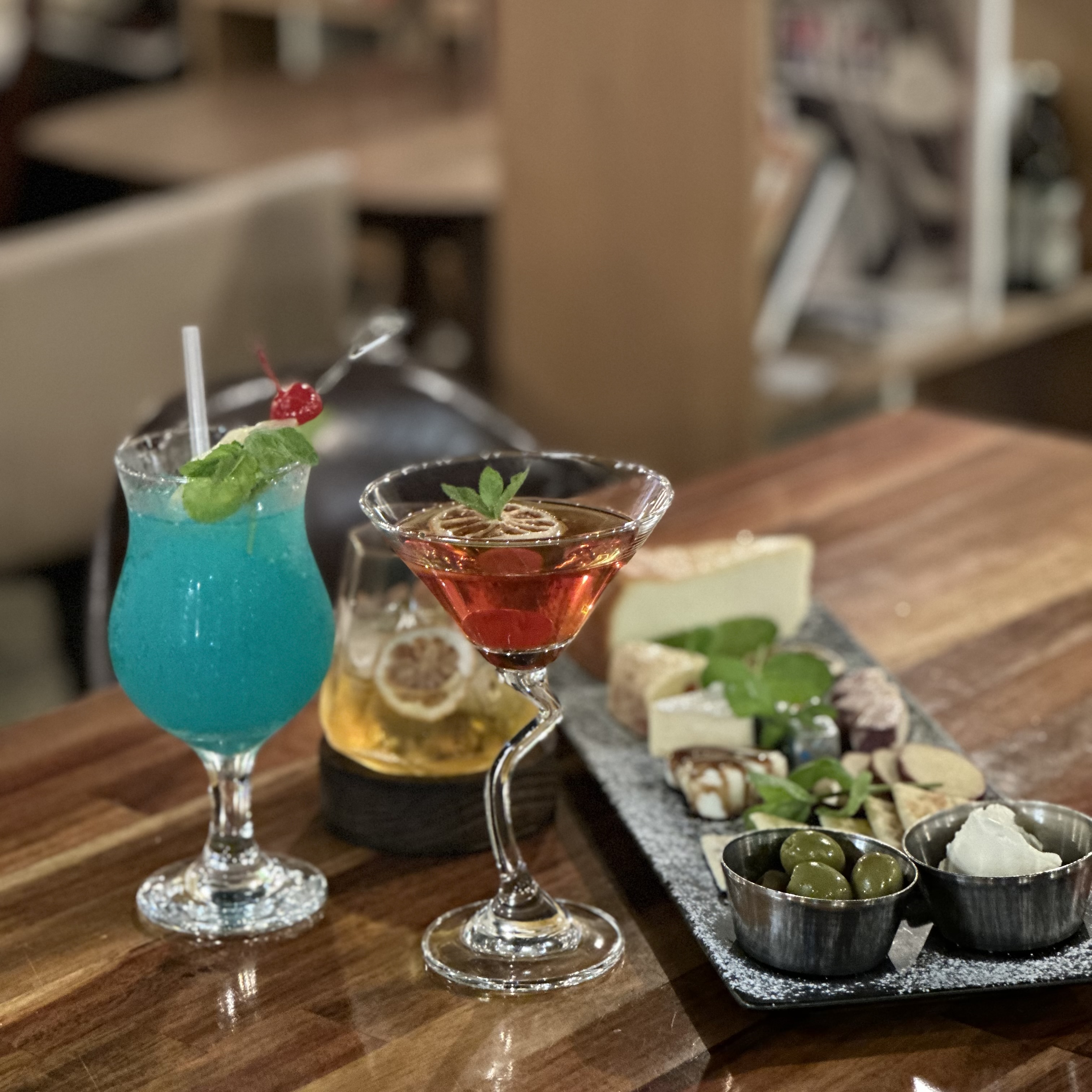 Cocktails and a cheese platter served on a wooden table at Deep Forest