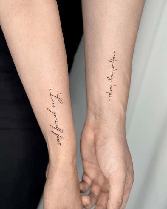 Two forearms showing minimalist cursive script lettering tattoos