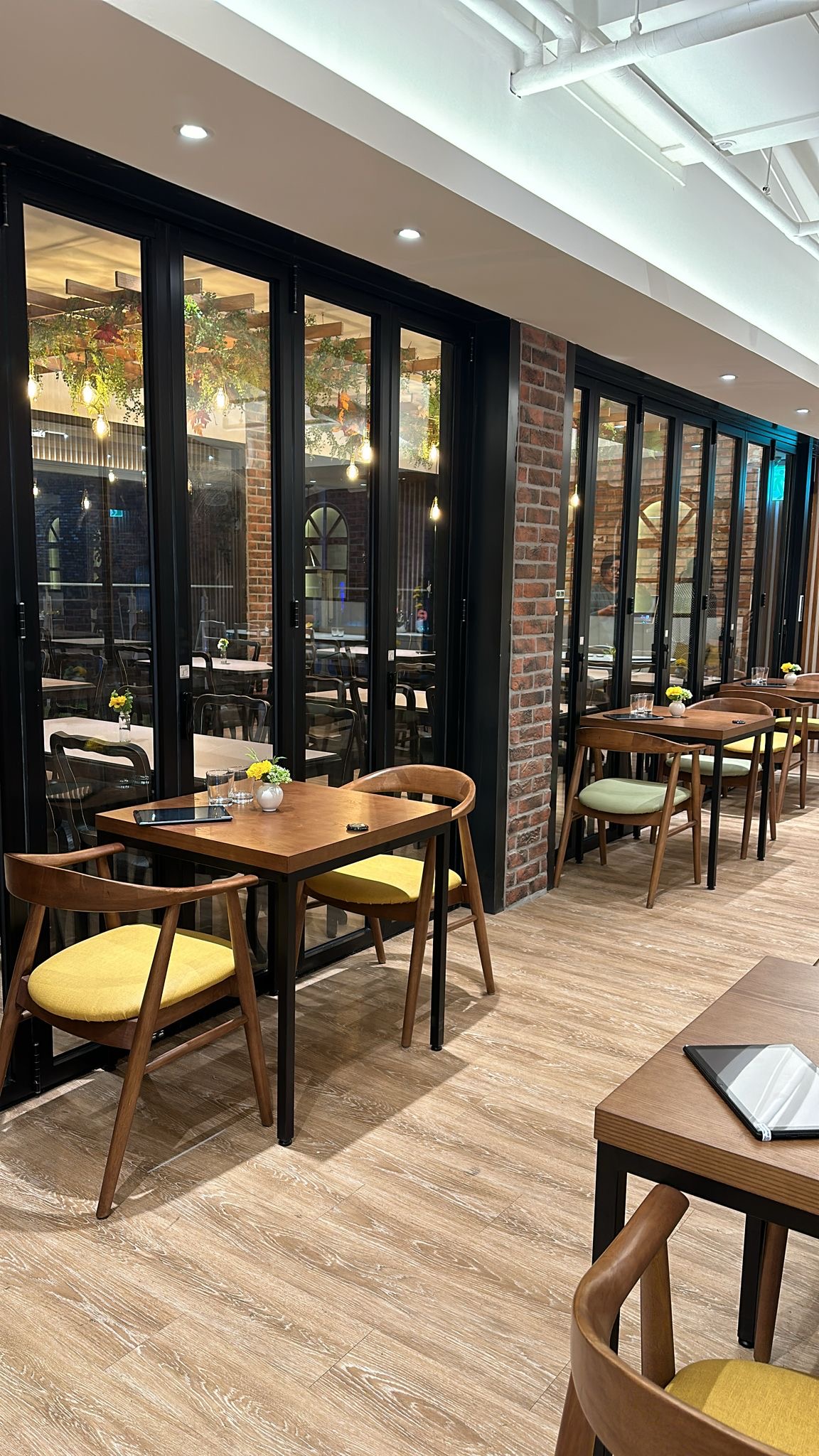 Bright dining space with wooden tables and exposed brick pillars at Saravanaa Bhavan Seoul