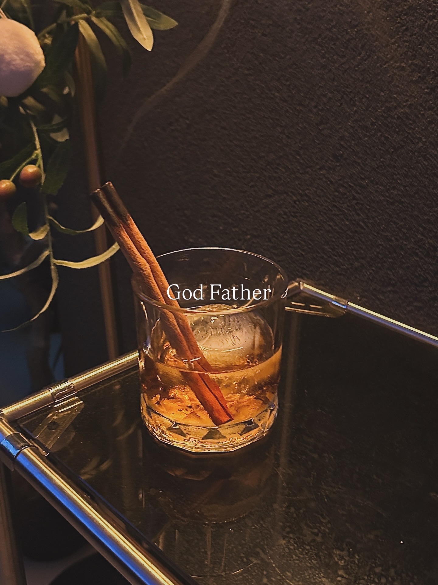 God Father cocktail with ice sphere and cinnamon stick garnish in a rocks glass