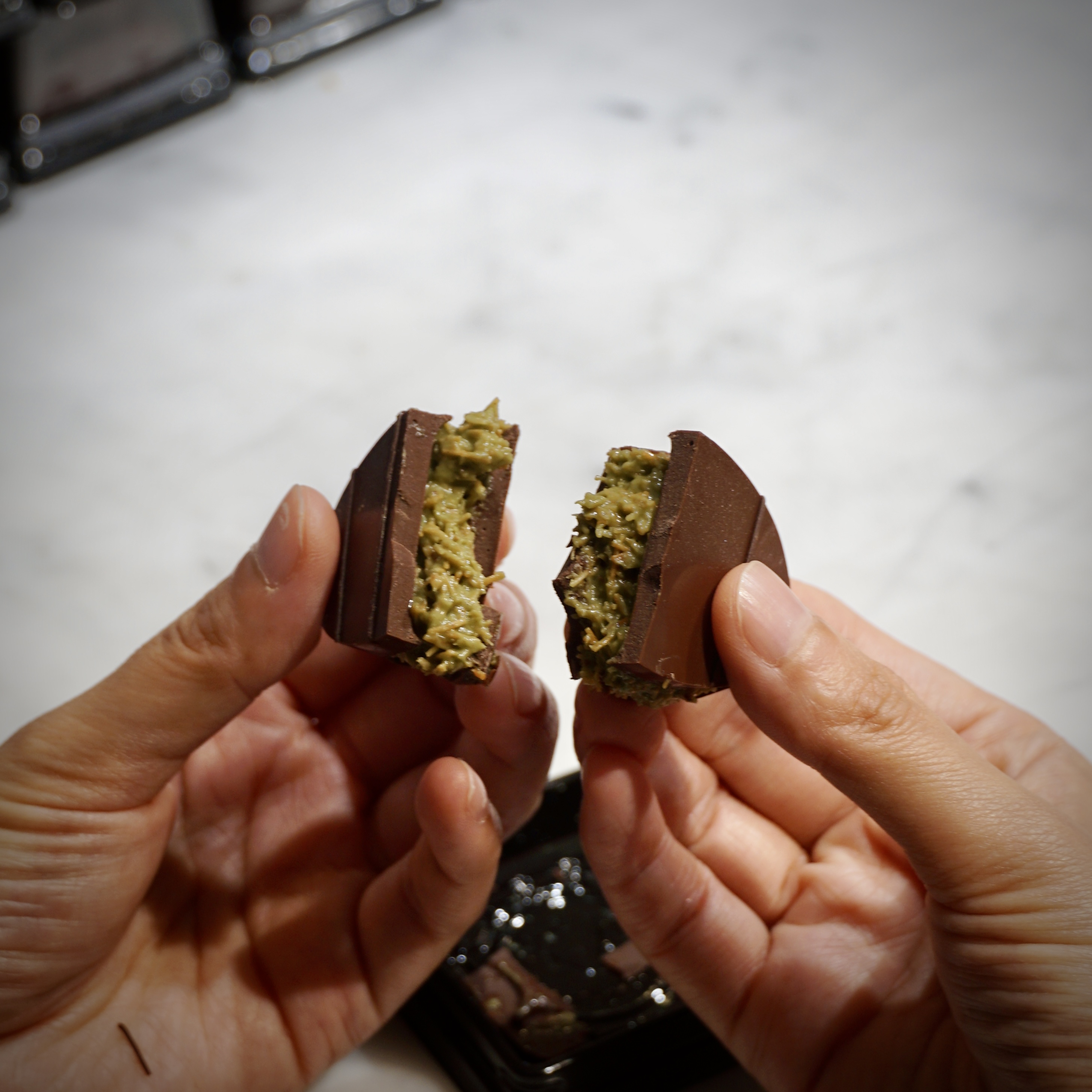 Broken chocolate shell revealing shredded kataifi and green pistachio cream filling