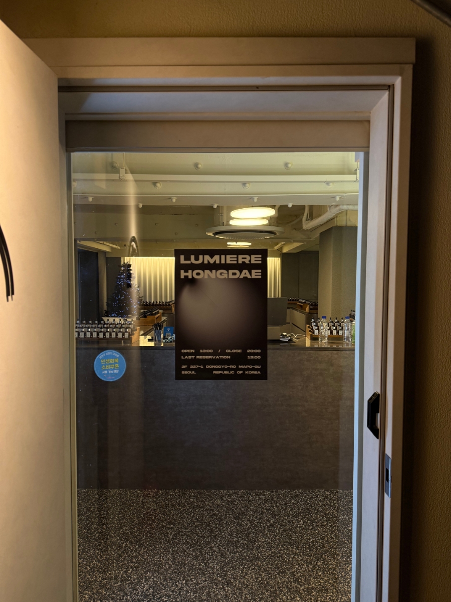 Entrance doorway into the Lumiere Hongdae perfume workshop with glass door and black sign