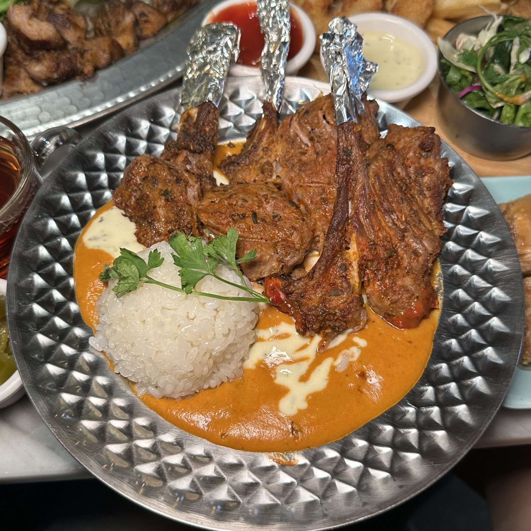 A plate of grilled lamb chops served with rice and savory sauce at Kervan Restaurant.