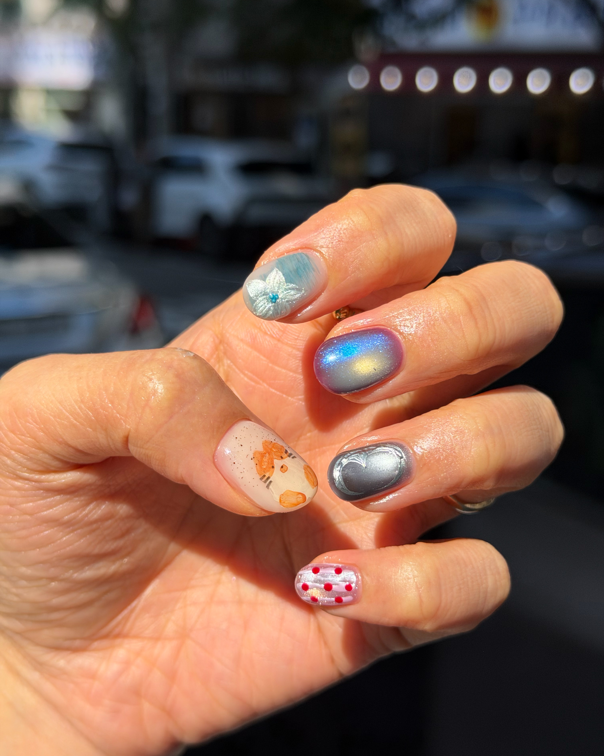 Close-up of hand showcasing aurora cat-eye and dimensional floral nail art
