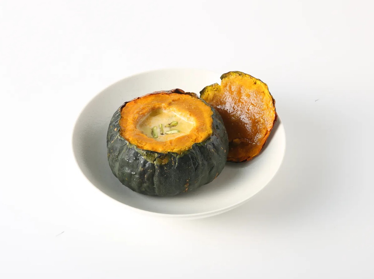 Signature roasted pumpkin filled with hot cream soup in an artisanal ceramic bowl