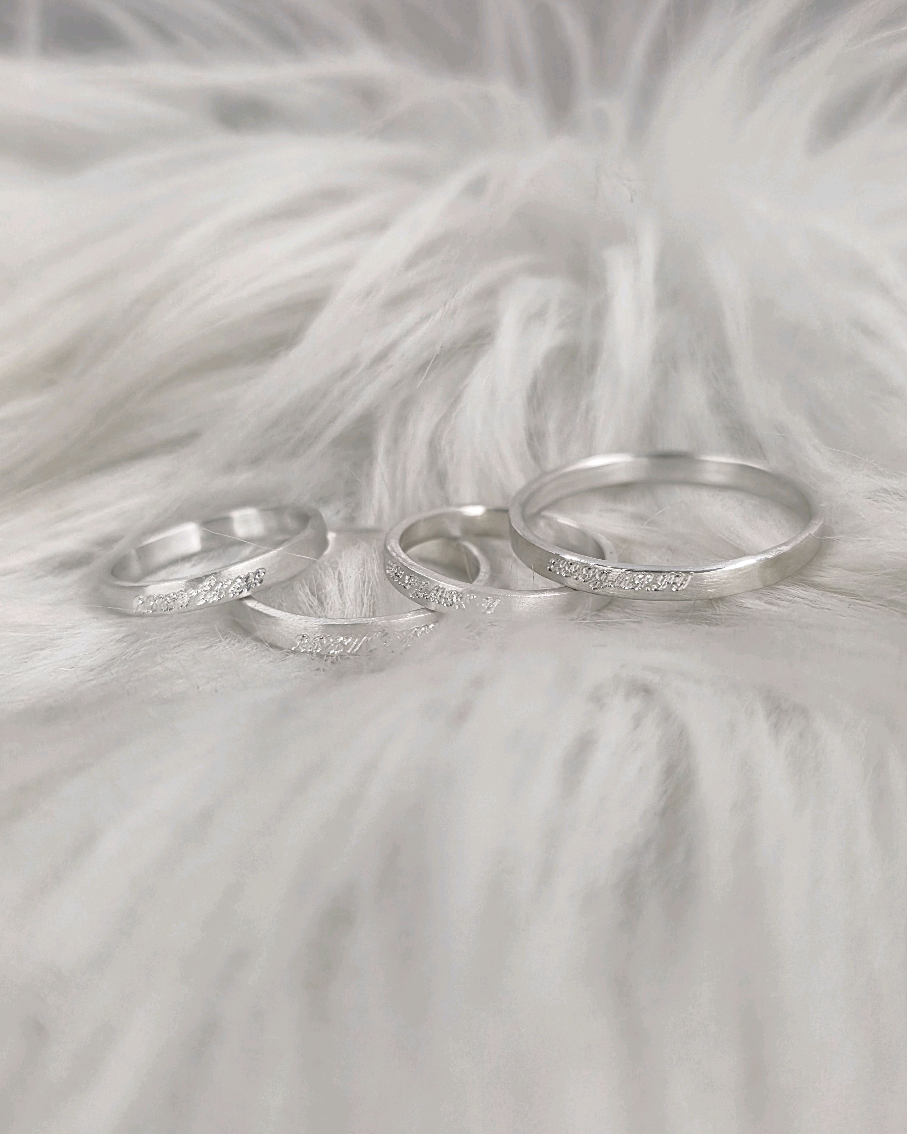 Three silver rings with textured detailing placed on a white faux fur surface