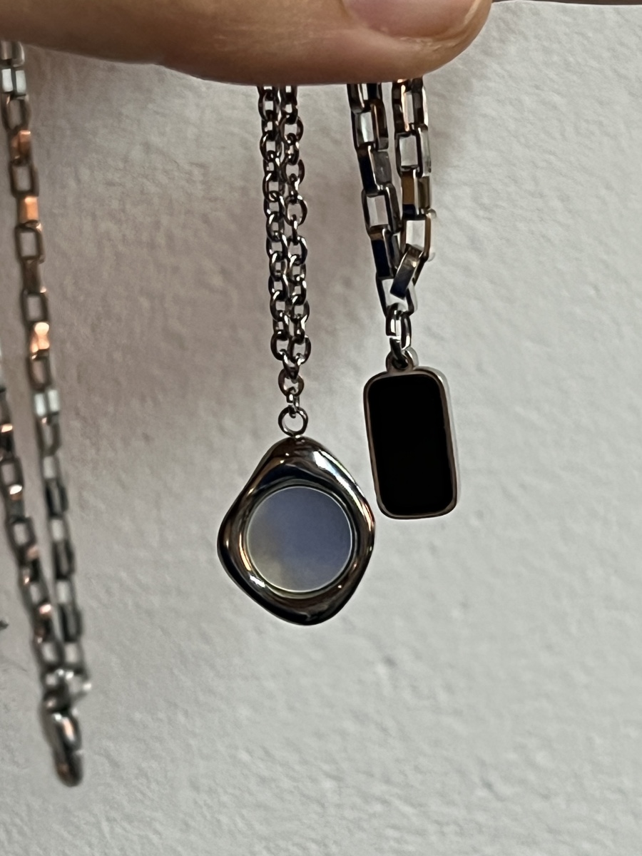 Silver necklaces held by fingers