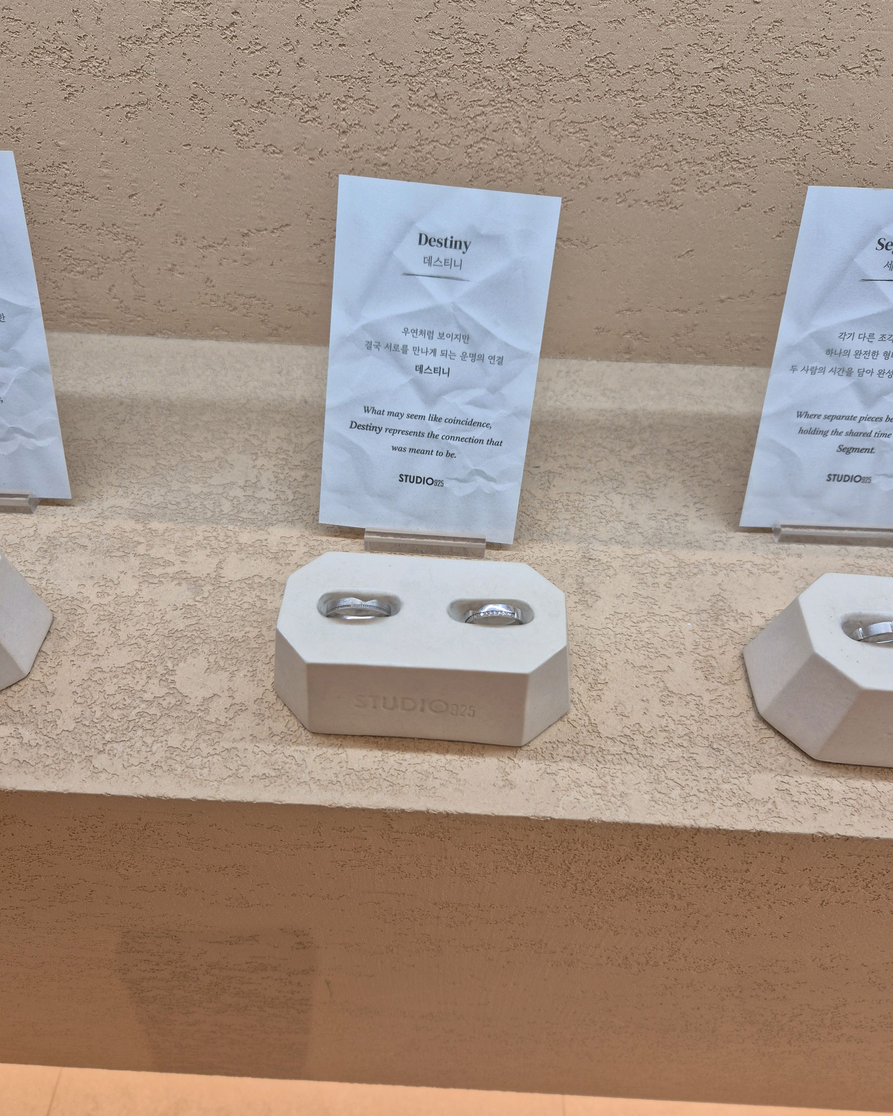 Pair of silver rings displayed on stone stand with Studio 925 card