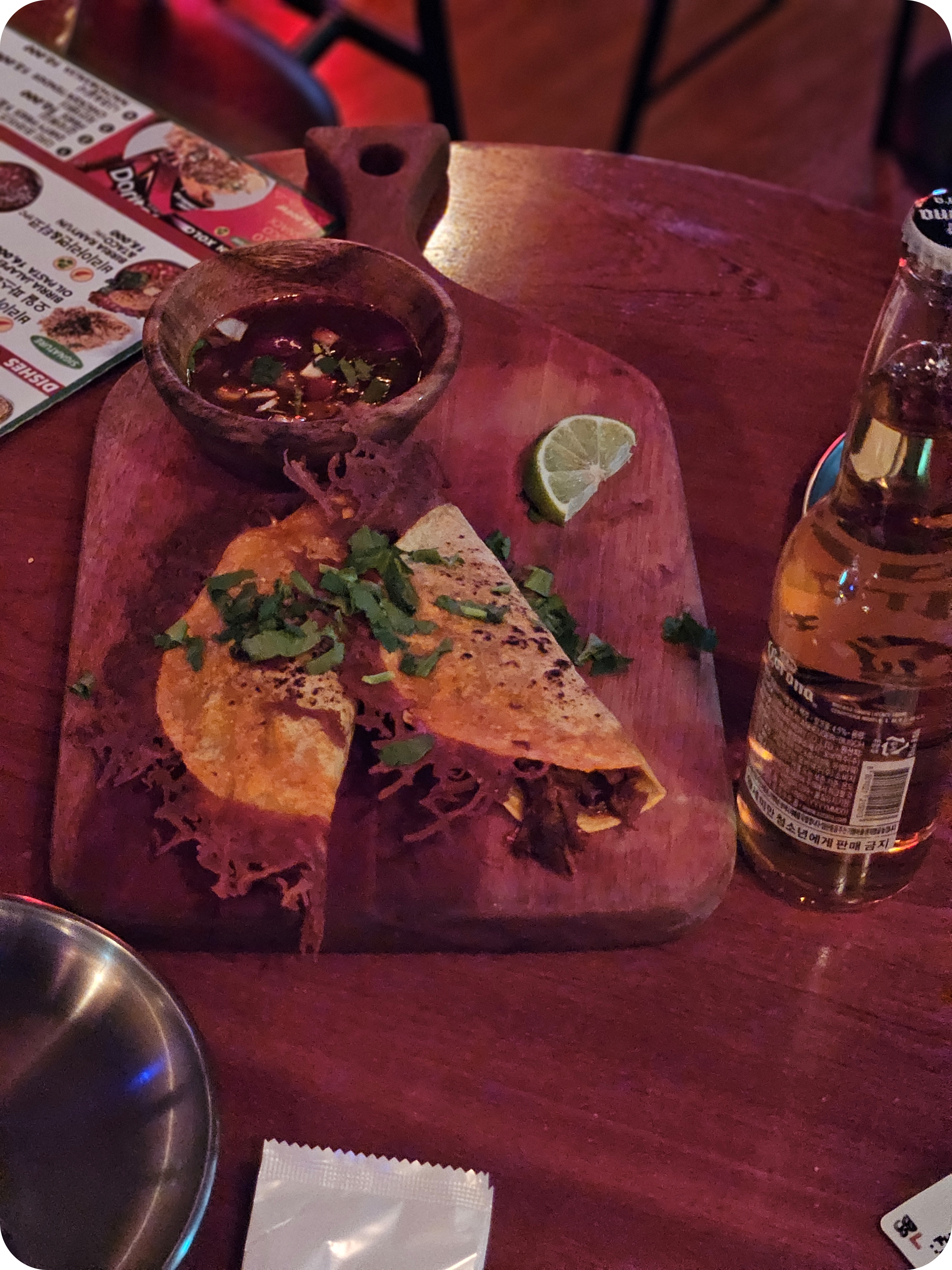 Two crispy tacos served with savory red dipping sauce on a wooden board