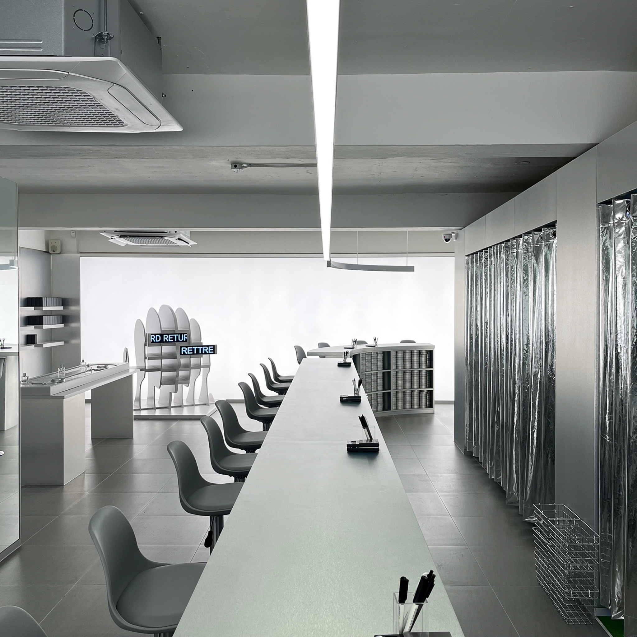 Central workbench with grey chairs and metallic curtains in the perfume atelier