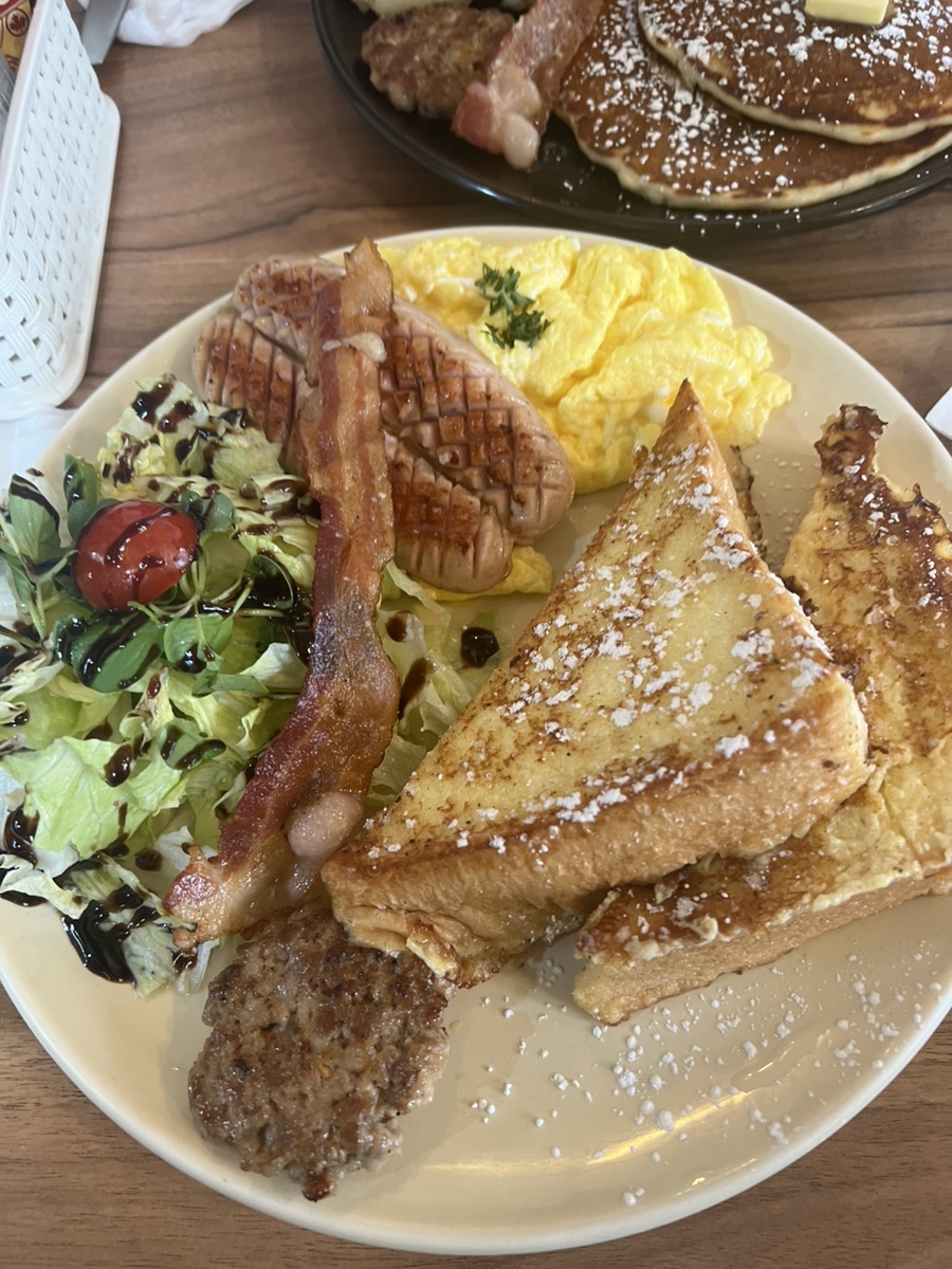 French toast plate with scrambled eggs, sausage patty, bacon, and salad