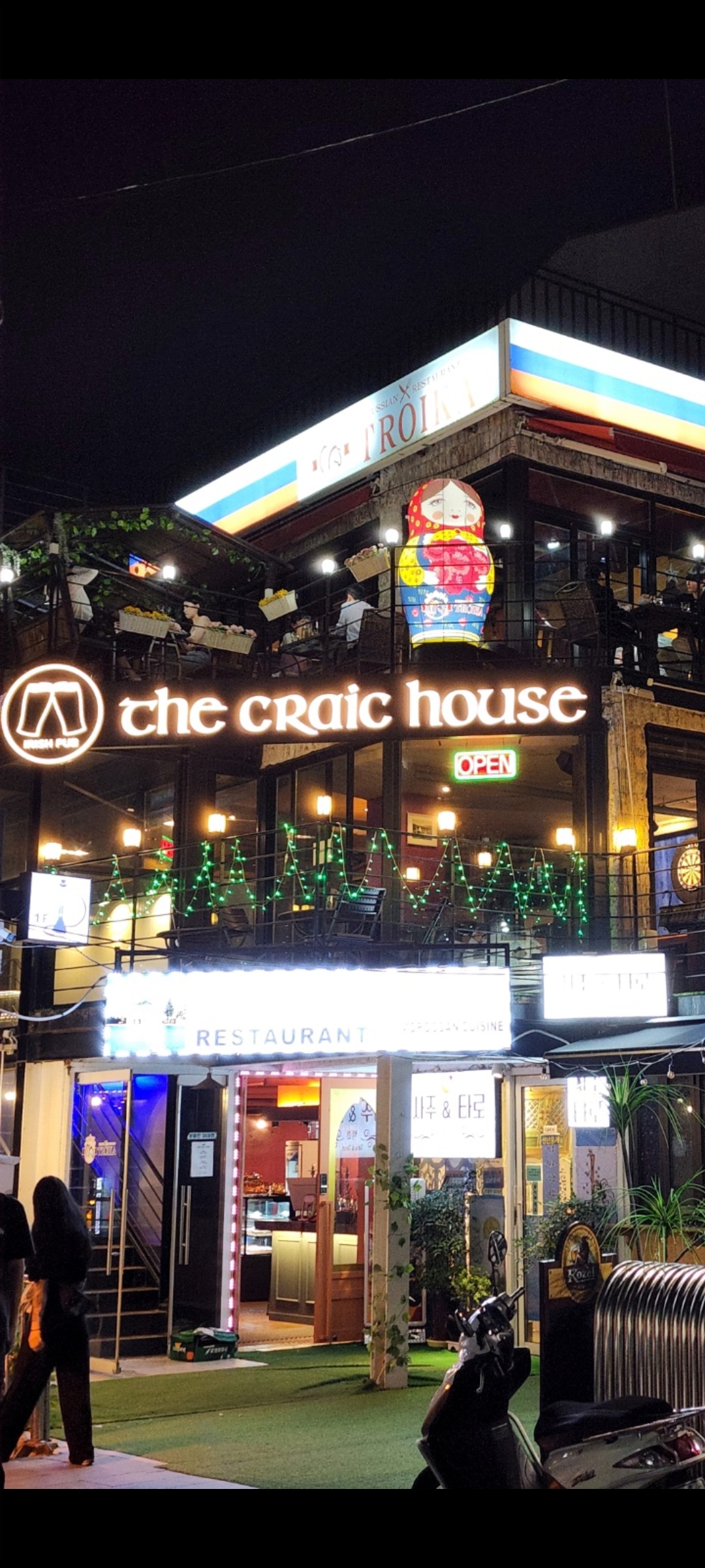 Night exterior view of The Craic House pub with lit sign on the 2nd floor in Itaewon